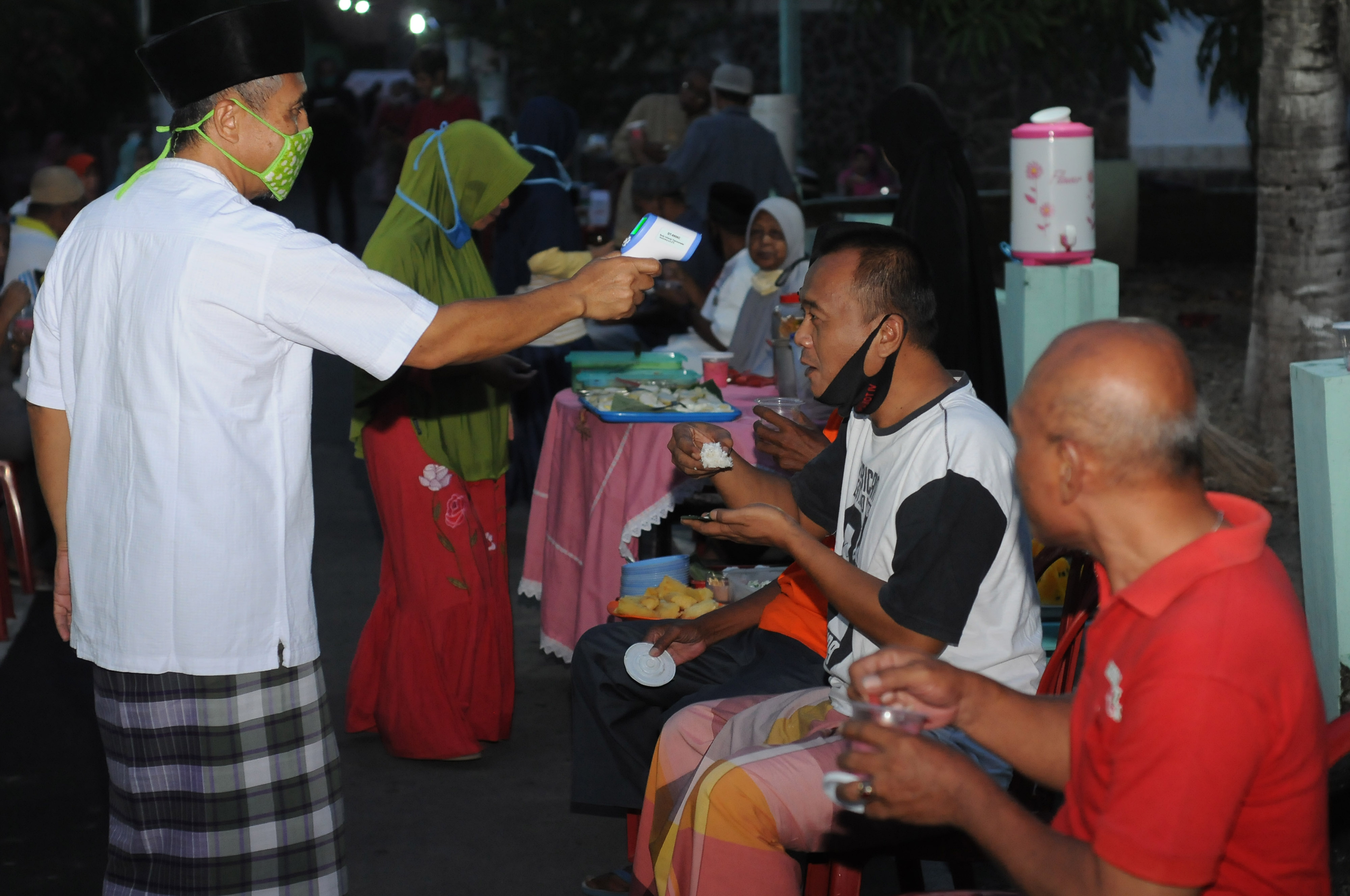 Seorang panitia mengecek suhu tubuh warga saat mengikuti berbuka puasa bersama di Banyudono, Boyolali, Jawa Tengah, Minggu (17/5/2020). 
