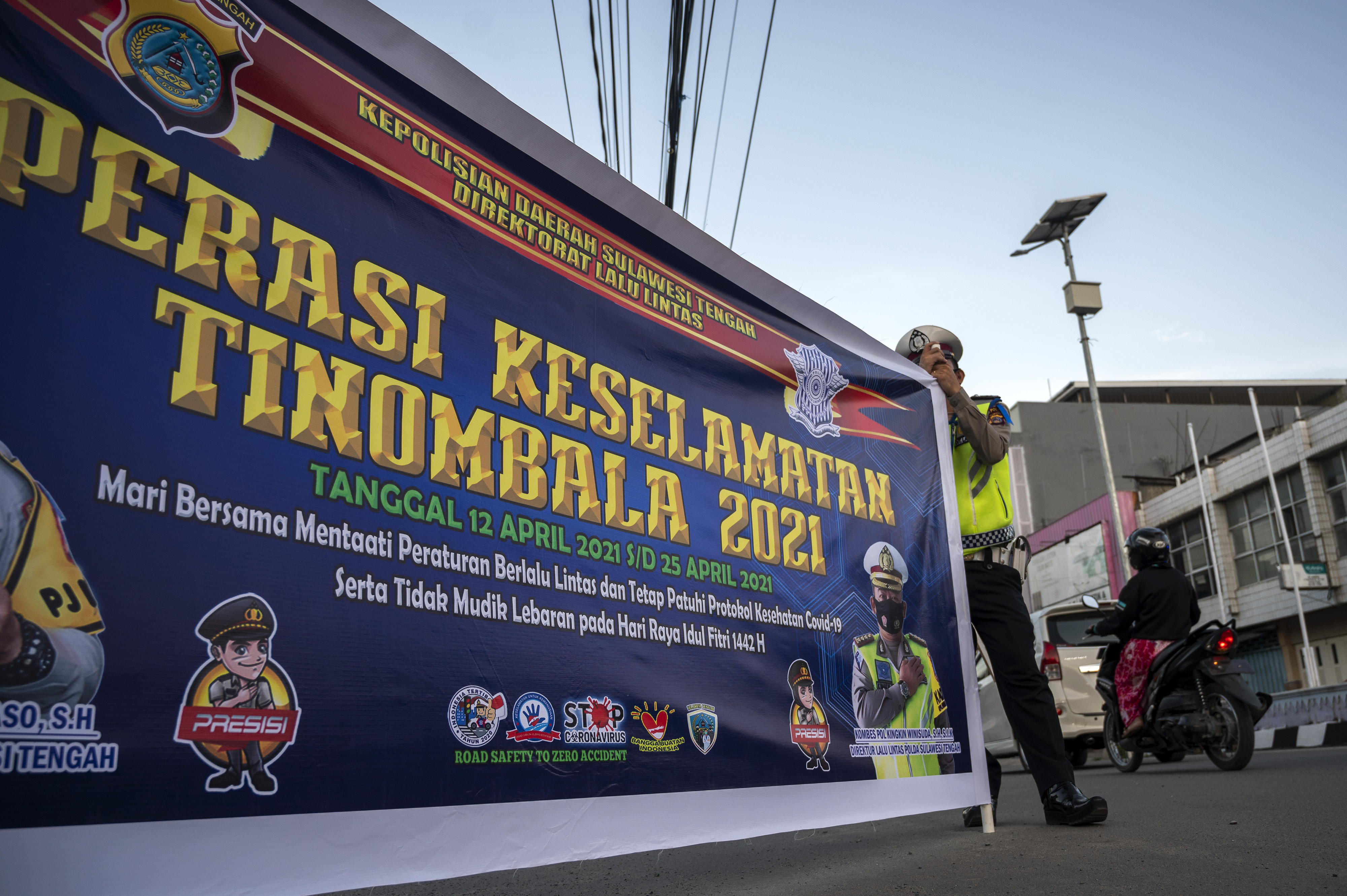 Polisi membentangkan spanduk saat Operasi Keselamatan Tinombala 2021 di salah satu ruas jalan di Palu Sulawesi Tengah, Jumat (16/4/2021).