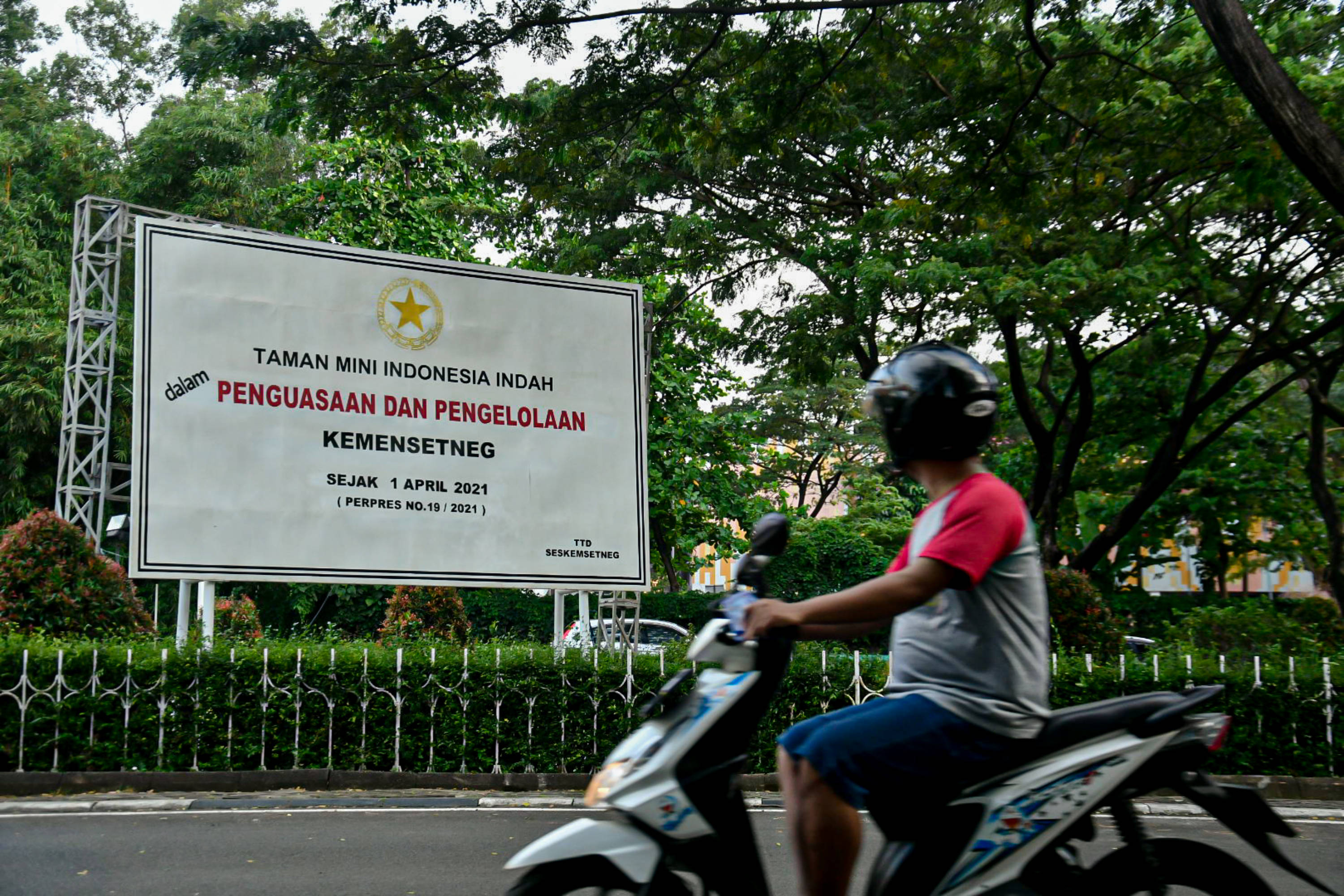 Pengendara melintas di depan baliho pengumuman pengambilalihan pengelolaan TMII oleh Kemensetneg' di depan pintu gerbang TMII, Jakarta.