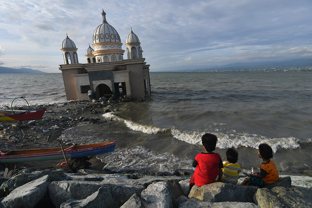 Warga menunggu datangnya waktu berbuka puasa (ngabuburit) di sekitar Masjid Terapung Arkam Babu Rahman yang rusak akibat diterjang tsunami.