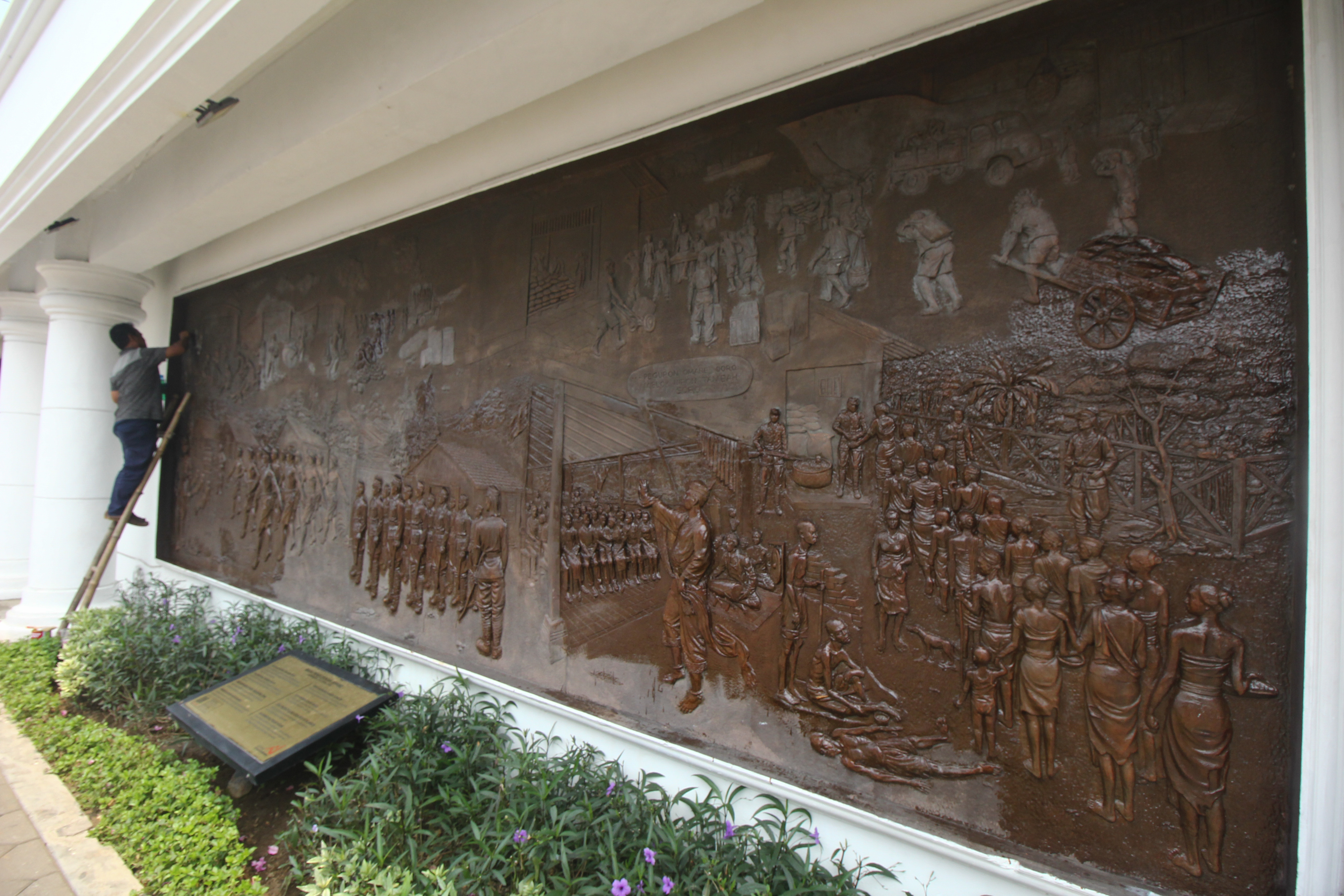 Pekerja membersihkan reliaf dinding di Tugu Pahlawan, Surabaya, Jawa Timur.