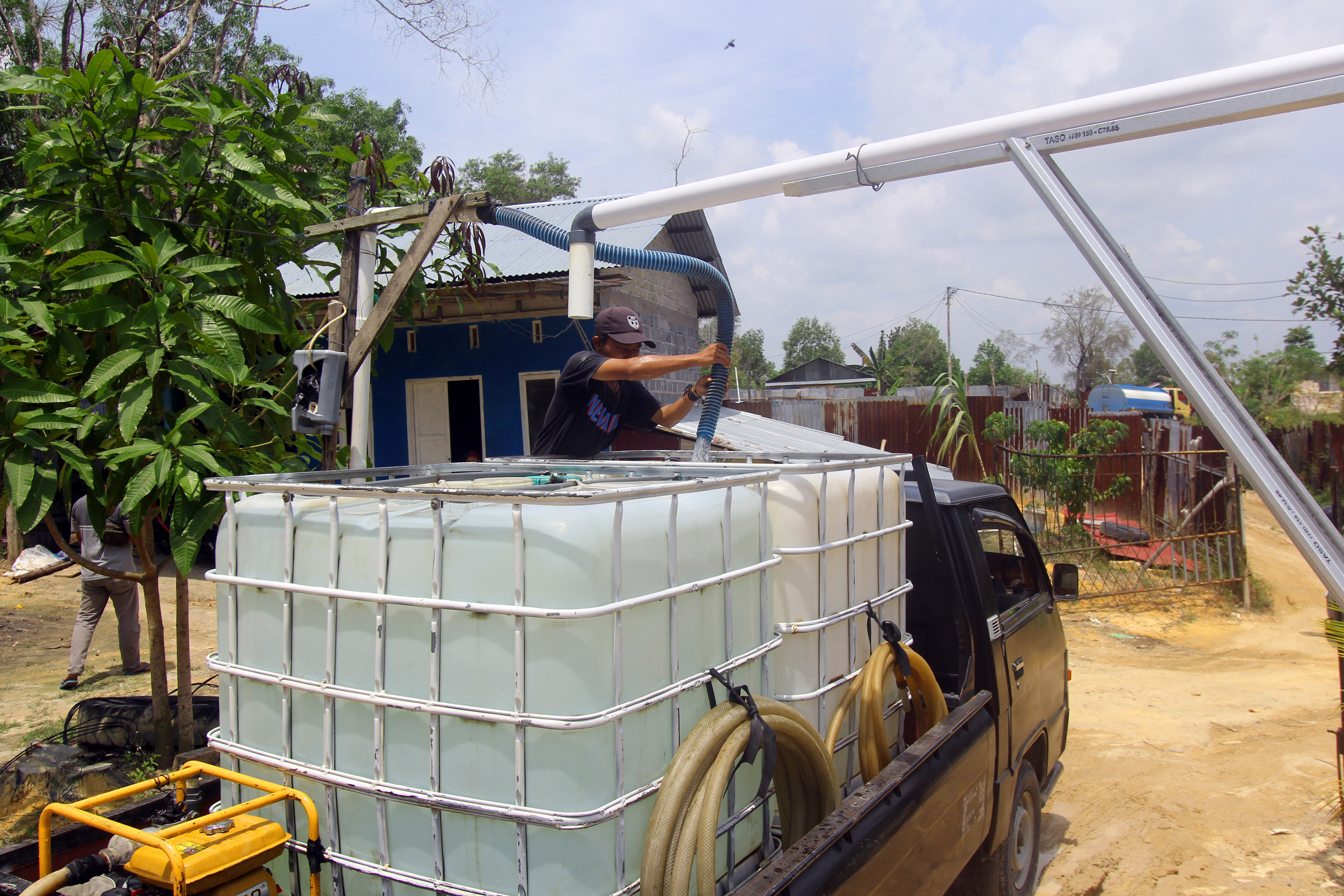  Seorang pekerja mengisi air bersih ke dalam tangki plastik di Bukit Cahaya Dumai, Riau, Senin (22/3/2021)