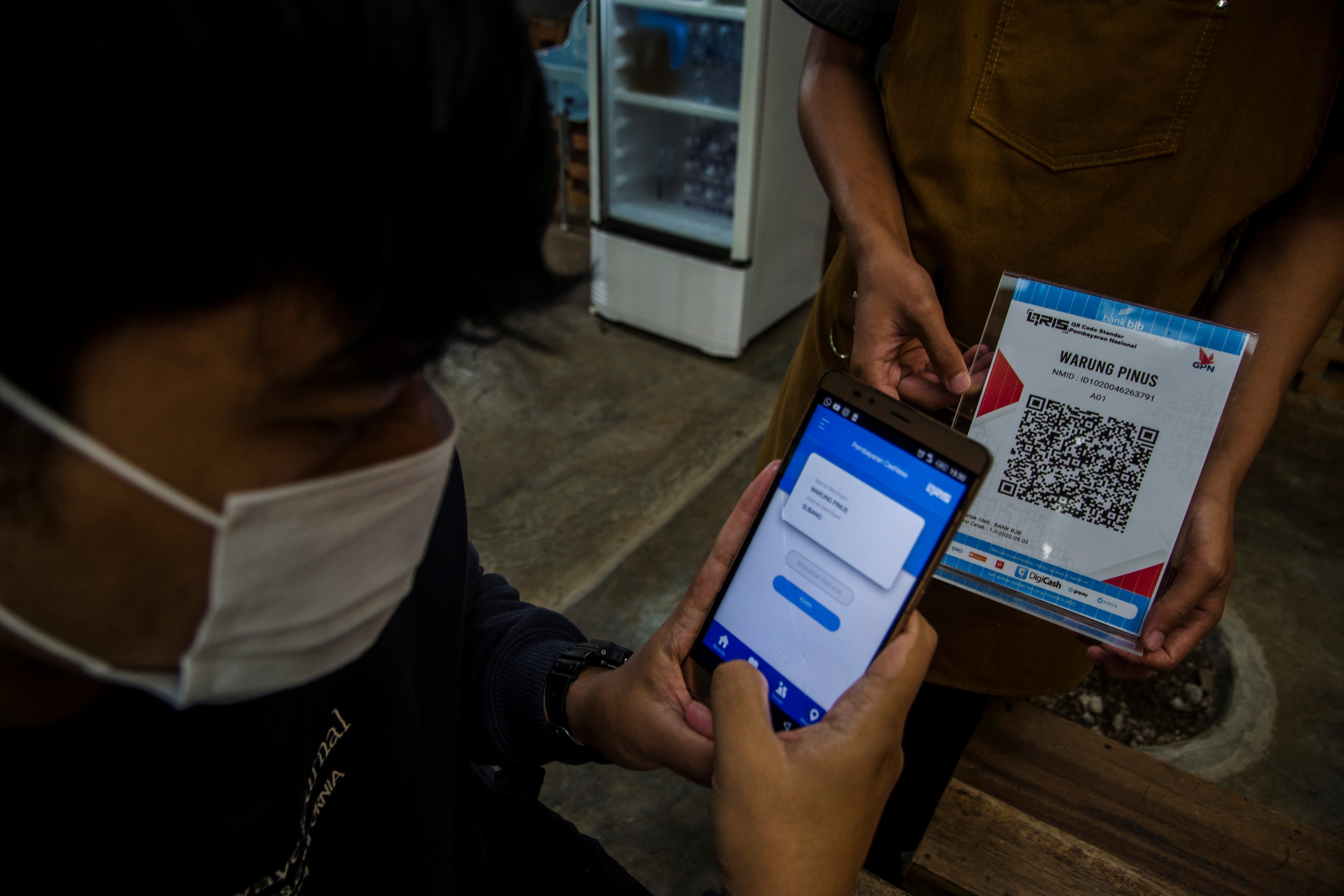 Konsumen melakukan transaksi pembayaran menggunakan aplikasi uang elektronik suatu bank.