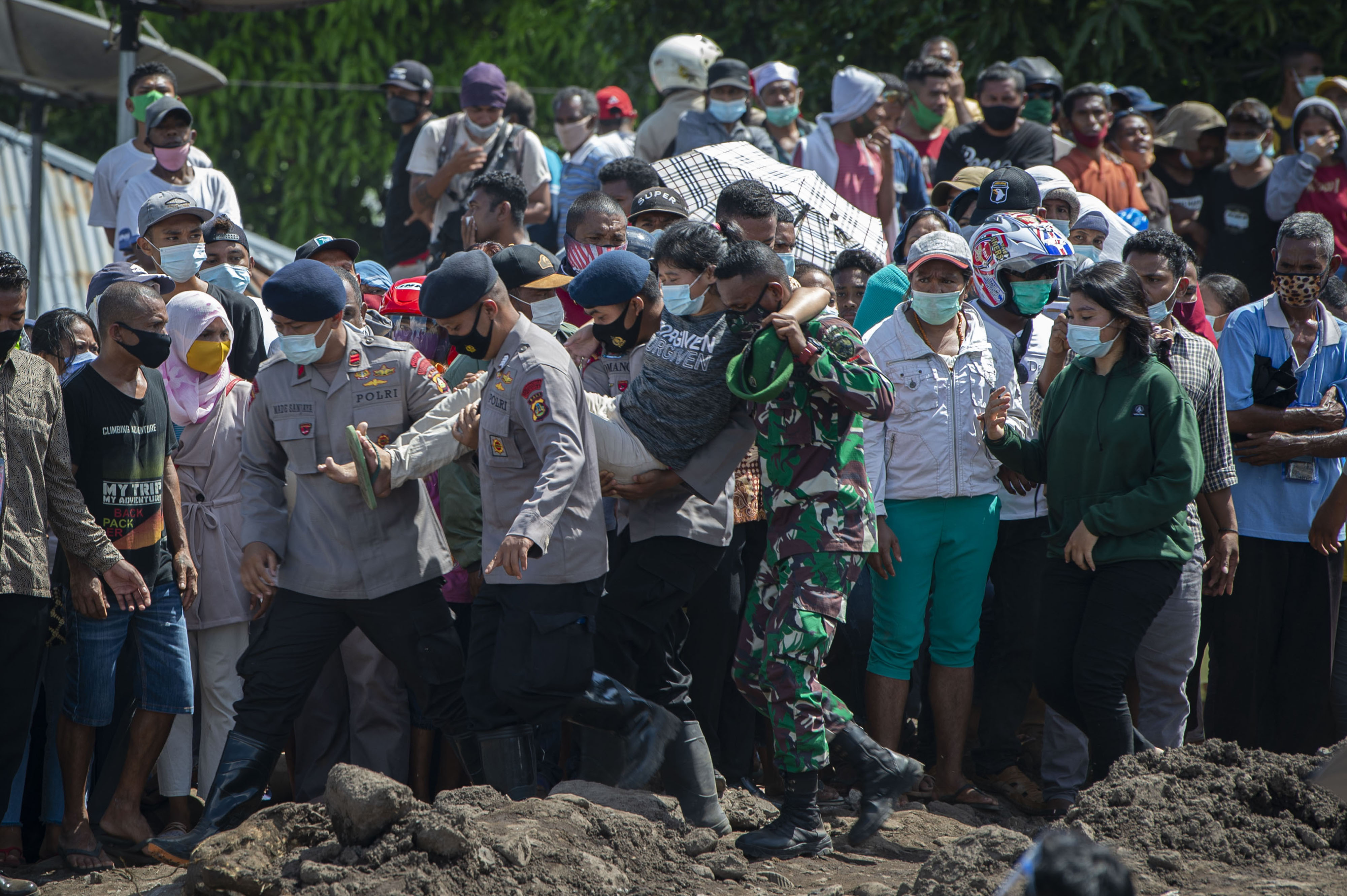 Warga yang pingsan digendong oleh aparat TNI-Polri saat menyambut Presiden Jokowi di Lokasi Banjir Bandang, Adonara, NTT.