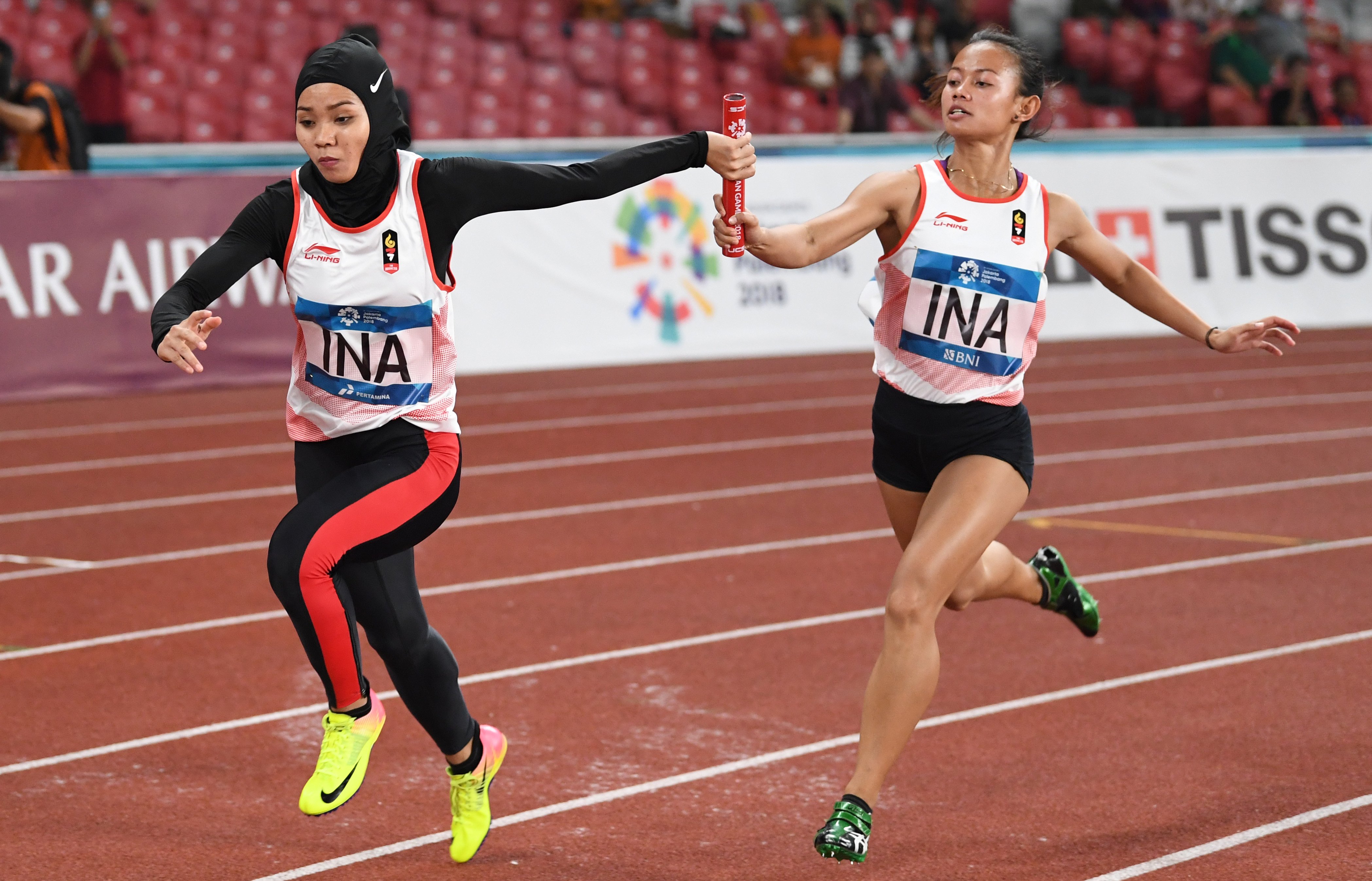 Pelari Indonesia Tyas Murtiningsih (kanan) menyerahkan tongkat kepada Yuliana pada penyisihan lari estafet 4x100m Putri Asian Games 2018.