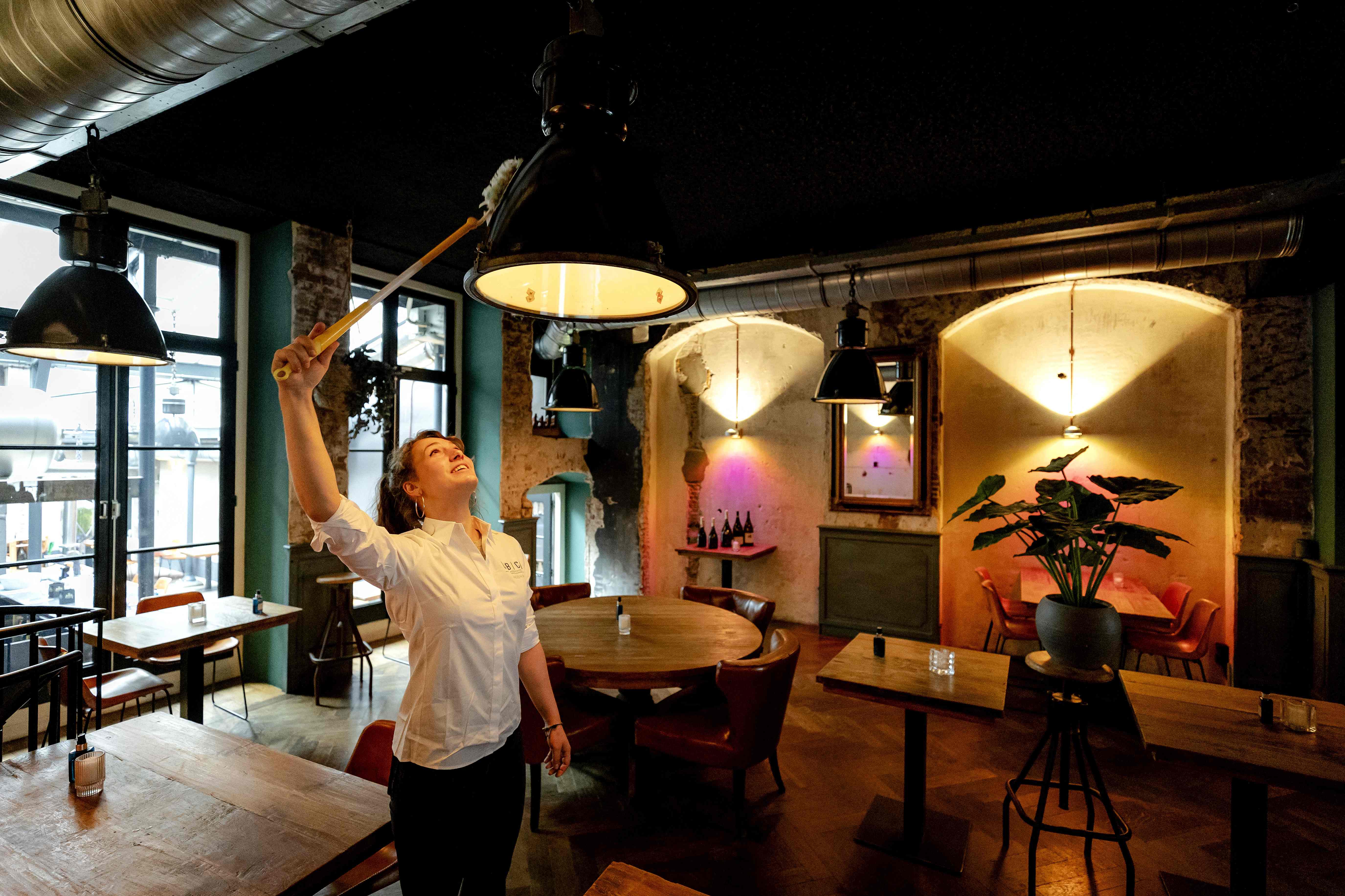 Petugas kafe melakukan persiapan buka dengan bersih-bersih ruangan