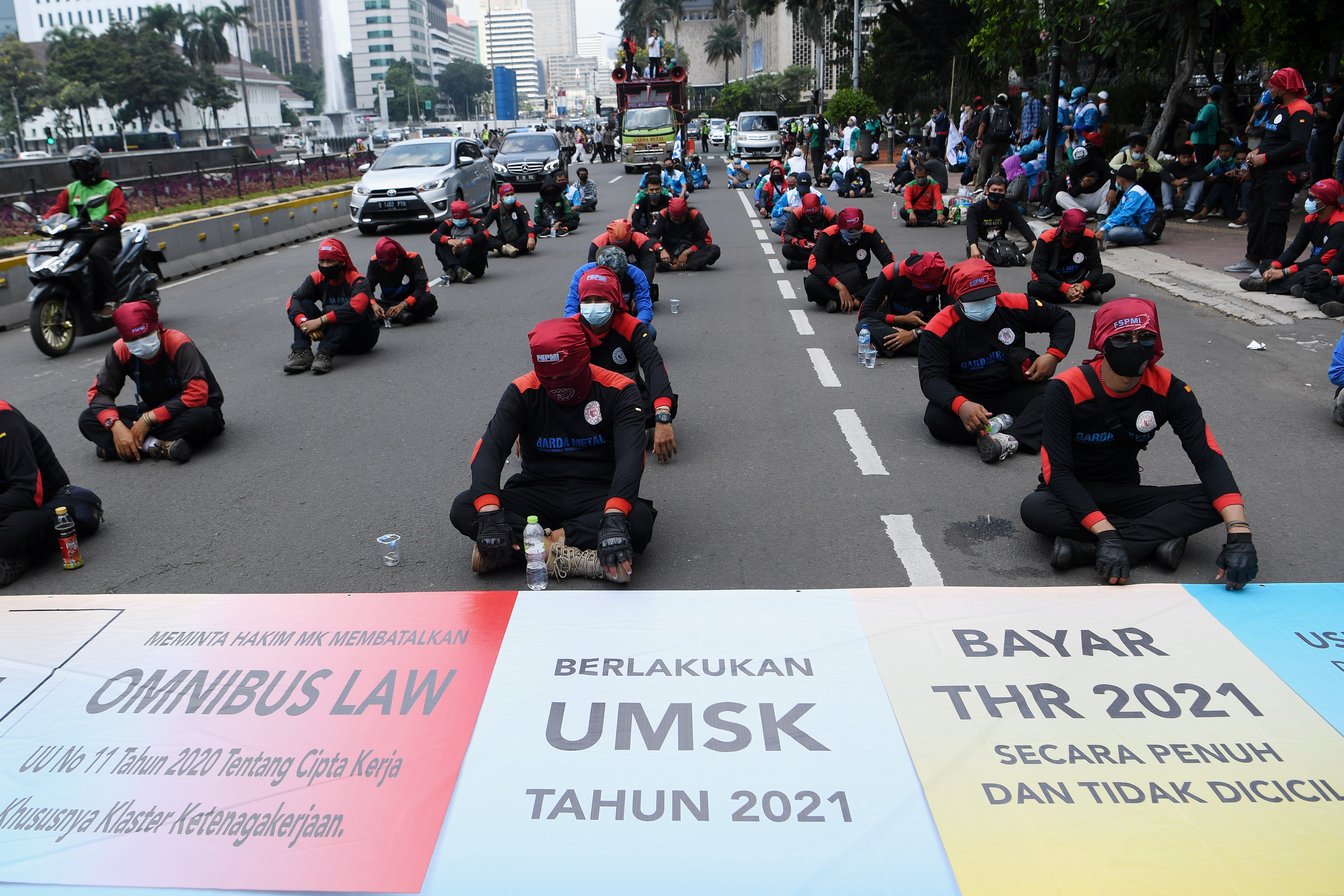 ejumlah buruh yang tergabung dalam Konfederasi Serikat Pekerja Indonesia berunjuk rasa di kawasan Patung Kuda, Jakarta, Senin (12/4/2021).
