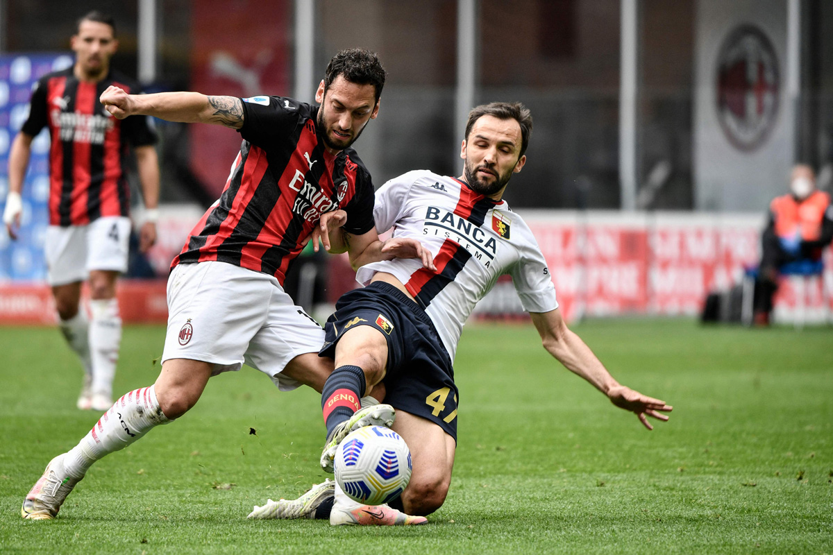 Gelandang AC Milan Hakan Calhanoglu (kiri) dihadang pemain Genoa dalam lanjutan Serie A Italia, Minggu (18/4). * _