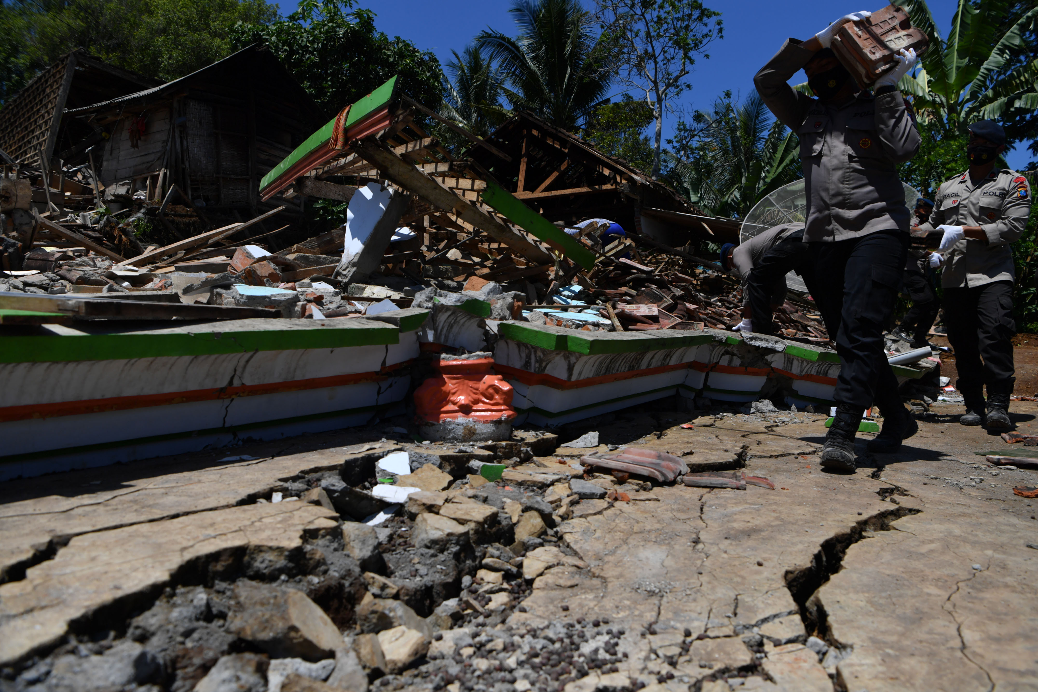 Sejumlah polisi membantu warga membersihkan puing bangunan yang rusak akibat gempa di Desa Kaliuling, Lumajang, Jawa Timur,Senin (12/4/2021)