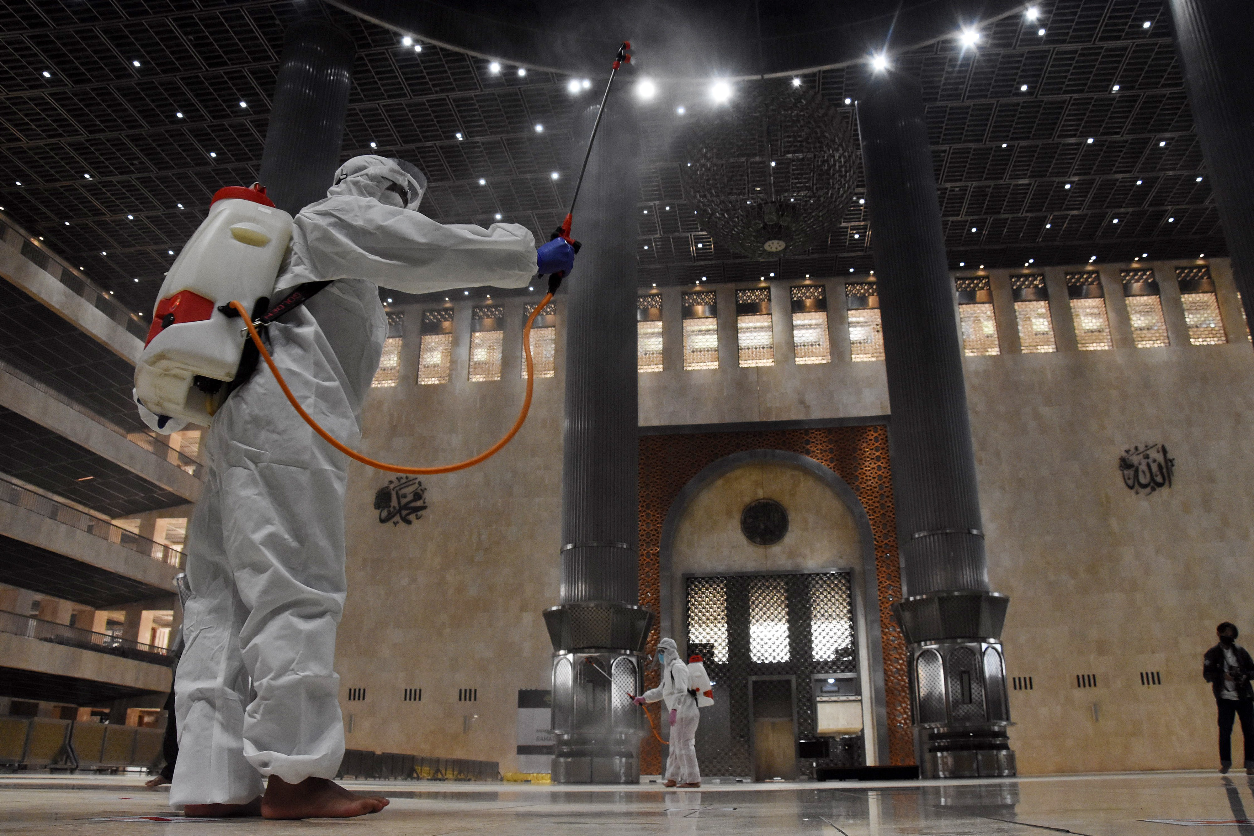 Petugas Palang Merah Indonesia (PMI) menyemprotkan cairan disinfektan di Masjid Istiqlal, Jakarta, Jumat (16/4).