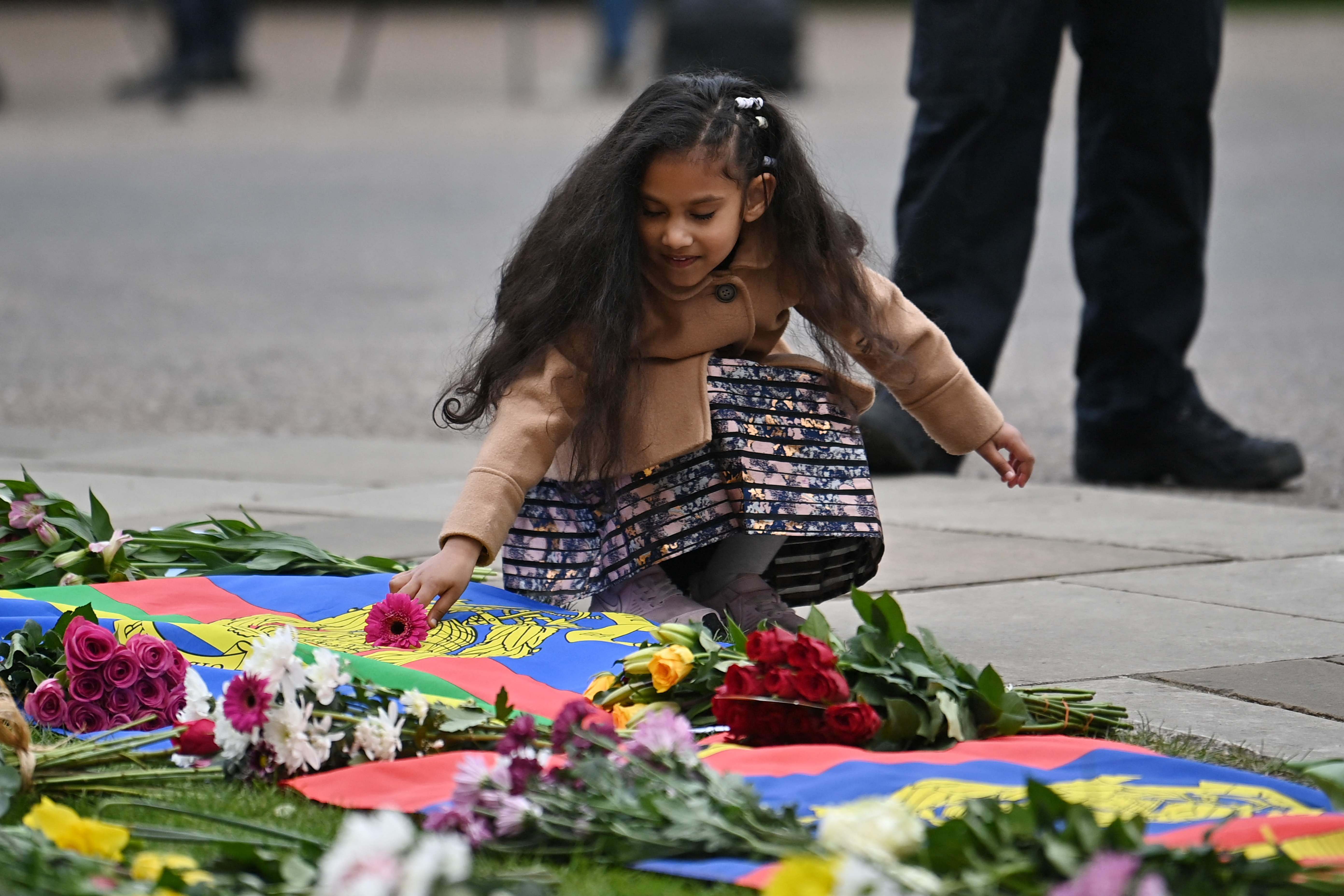 Seorang gadis menambahkan bunga untuk persembahan untuk Pangeran Philip di luar Kastil Windsor, Windsor, Jumat (9/4).