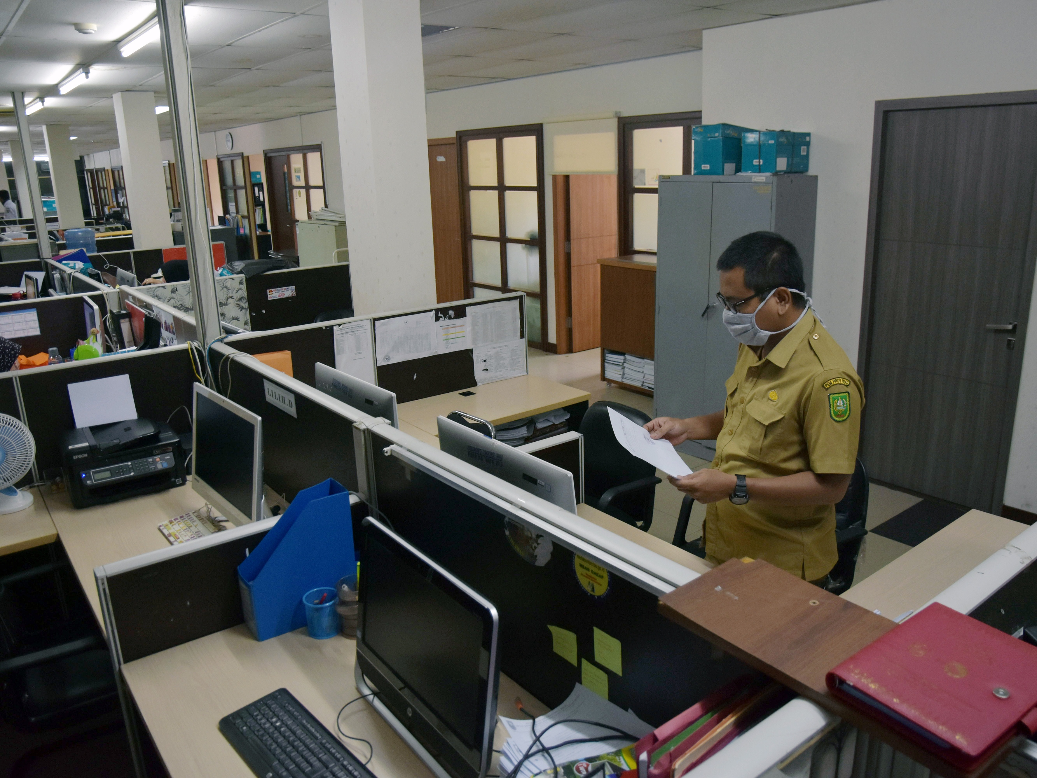 Seorang PNS Pemprov Riau mengenakan masker saat mendapat giliran masuk bekerja.