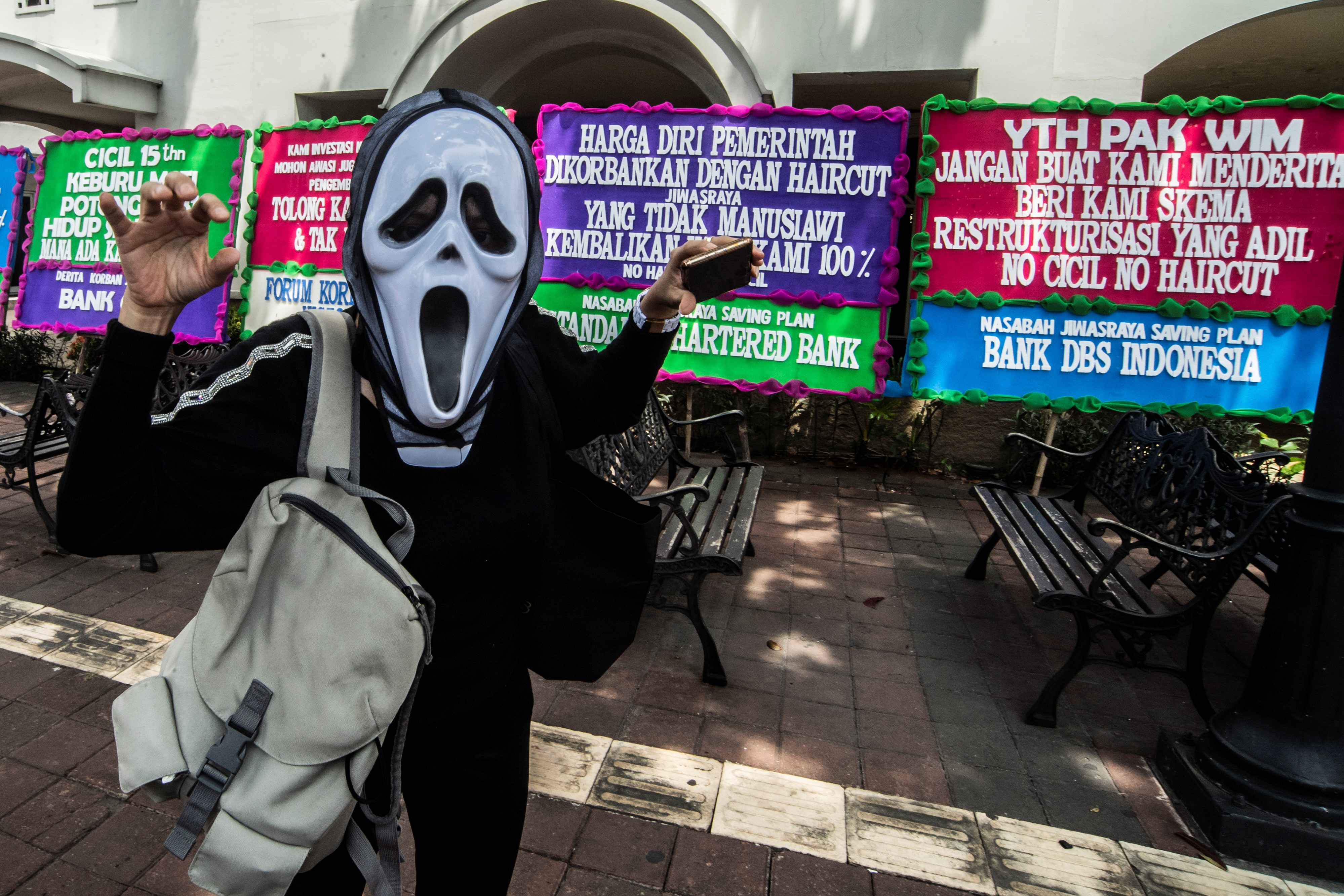 Salah satu nasabah pemegang polis Jiwasraya Saving Plan yang tergabung dalam Forum Korban Jiwasraya menggunakan topeng saat melakukan aksi.