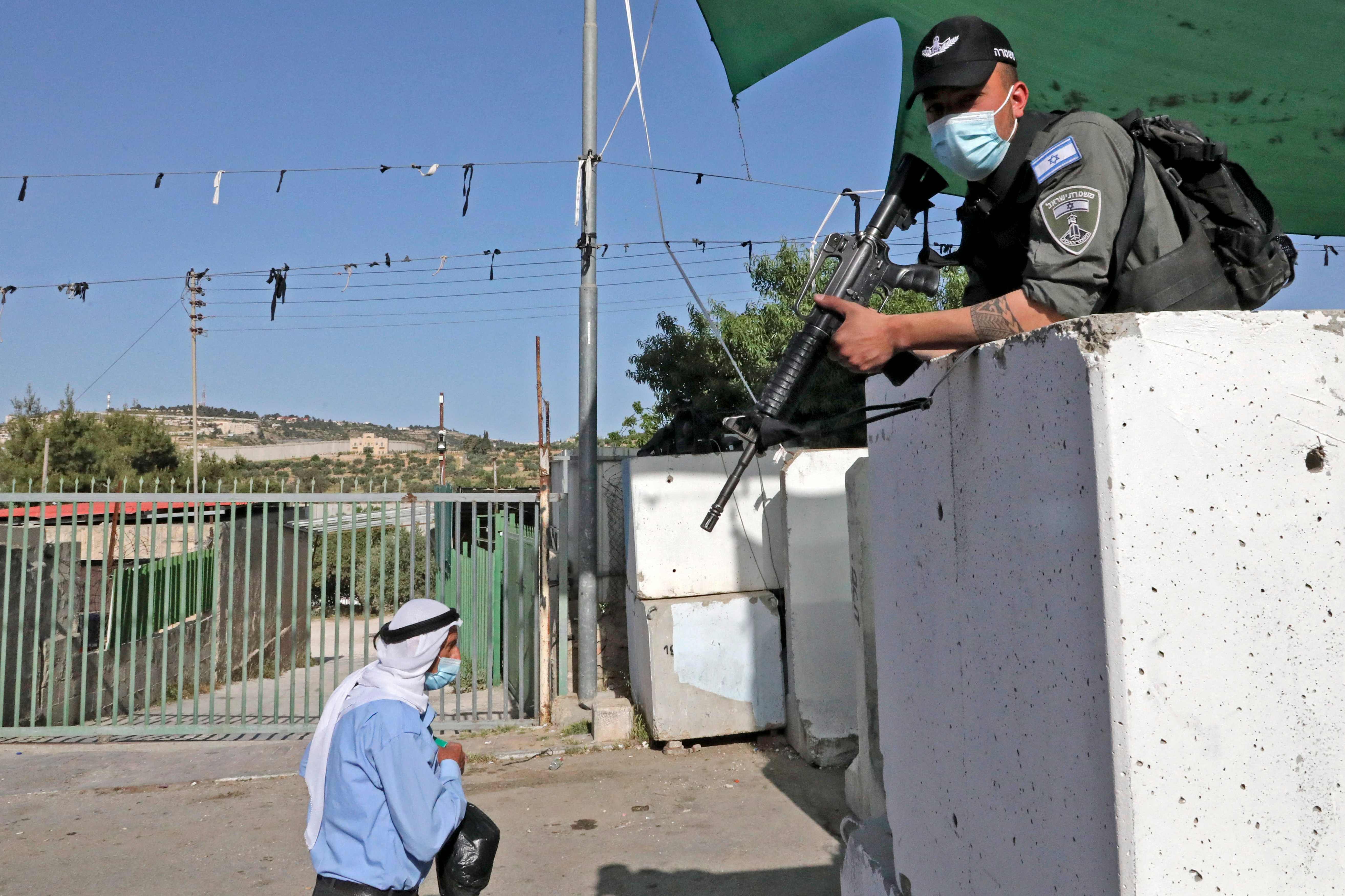 Seorang anggota pasukan keamanan Israel melihat seorang pria Palestina melalui pos pemeriksaan Betlehem di Tepi Barat.