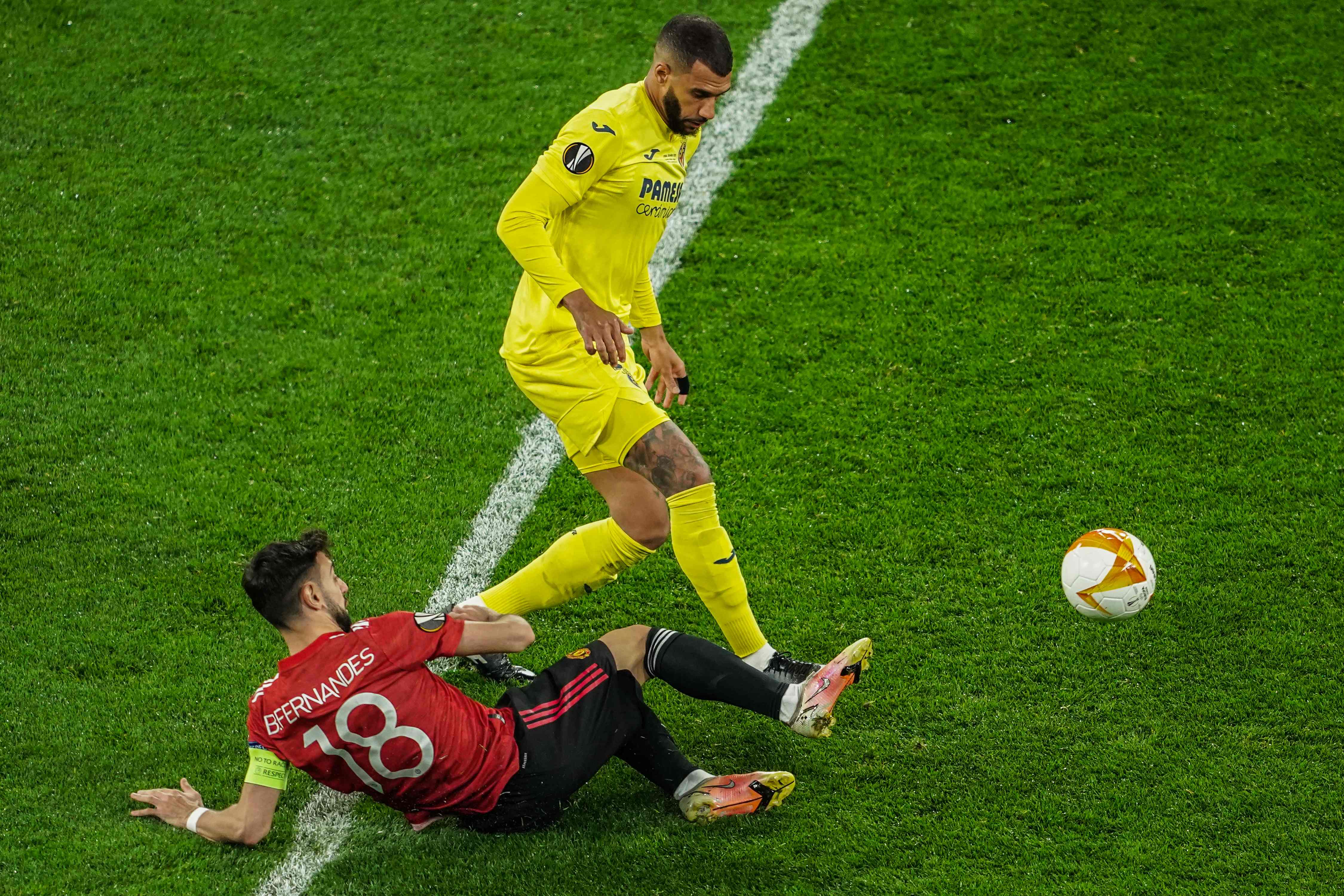 Gelandang Villareal, Etienne Capoue (berdiri), menggiring bola dan lolos dari jegalan kaki gelandang MU, Bruno Fernandes.  