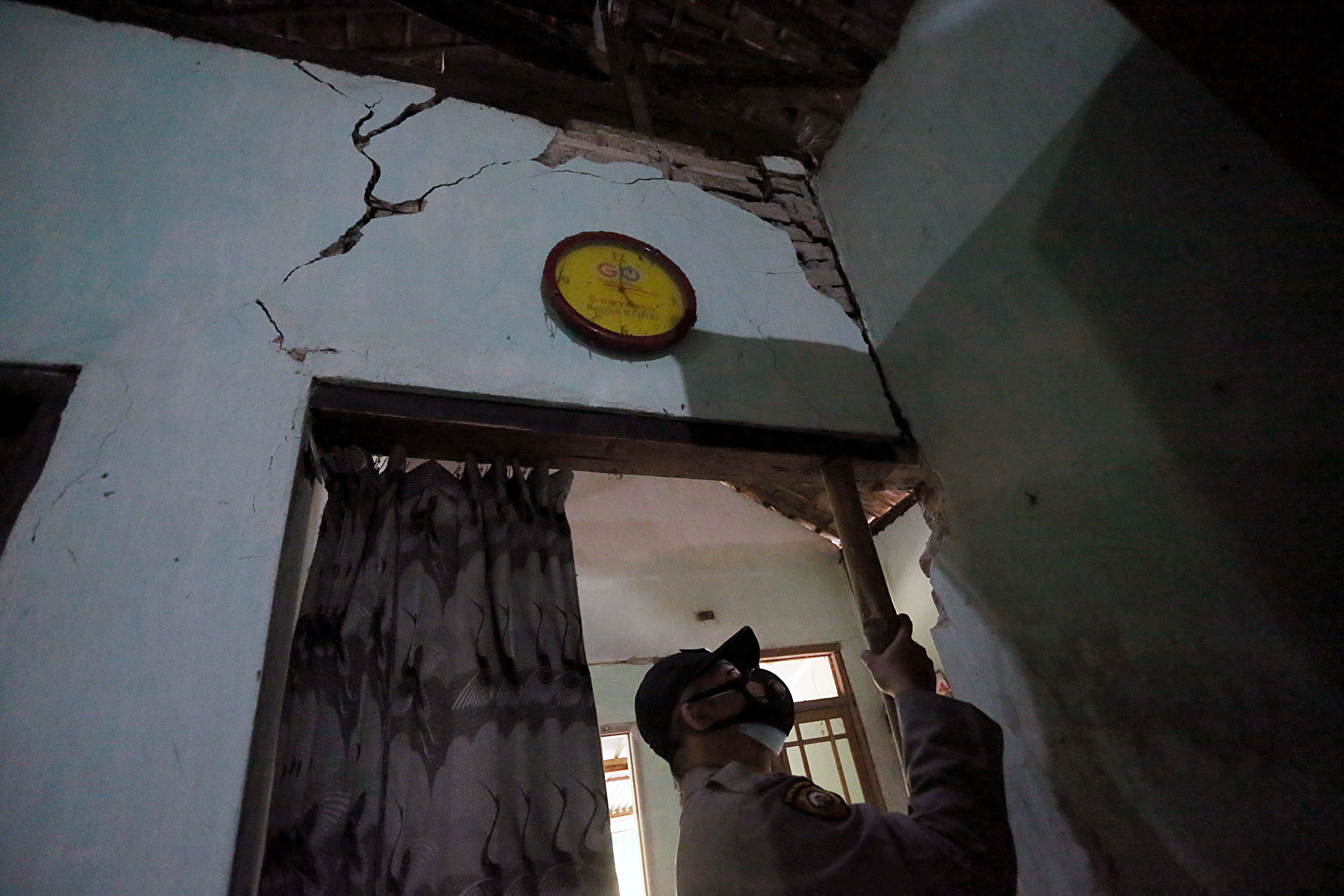 Petugas memasang tiang penyangga darurat di rumah yang rusak akibat gempa di Desa Jabung Kecamatan Talun, Blitar, Sabtu (22/5/2021).