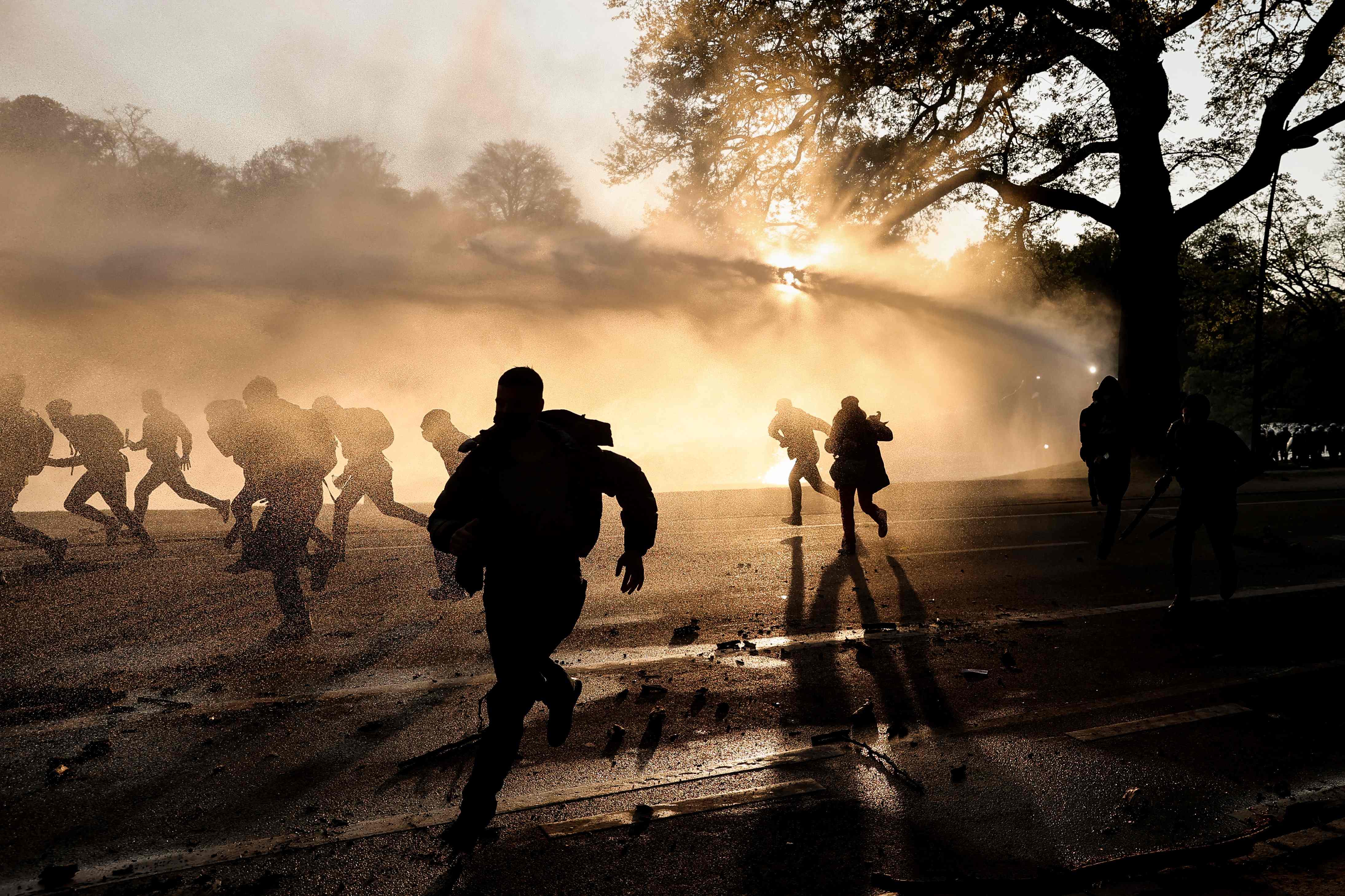 Demonstran melarikan diri saat polisi menembakkan meriam air di Brussels, Belgia.