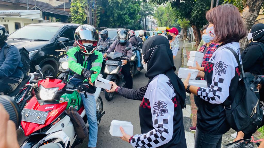 Anggota Moto Ladies membagikan tajil kepada pengendara.