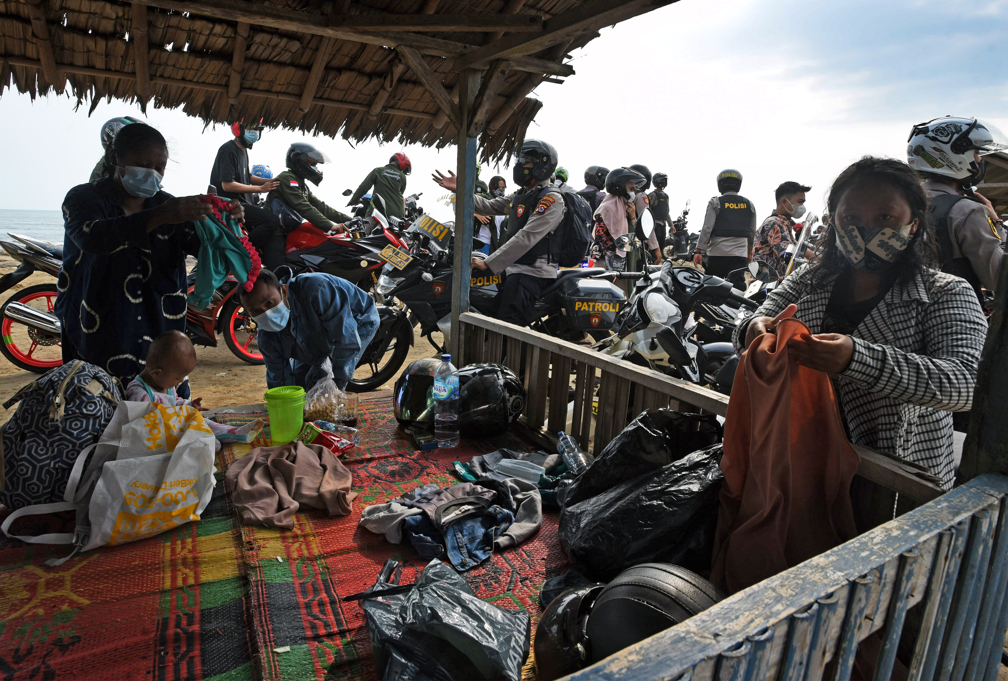 KERUMUNAN: Polisi membubarkan kerumunan para pengunjung yang sedang berwisata di Pantai Pasir Putih, di Anyer, Banten, Minggu (16/5/2021). 