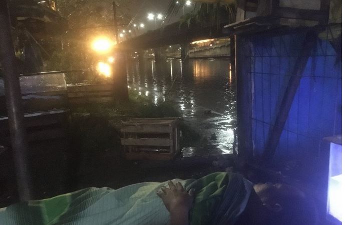 Seorang warga tertidur ketika berteduh di Pos Pemantauan Kali Ancol di Pintu Air Flushing Ancol, Pademangan, Jakut, Selasa (18/5) dini hari.