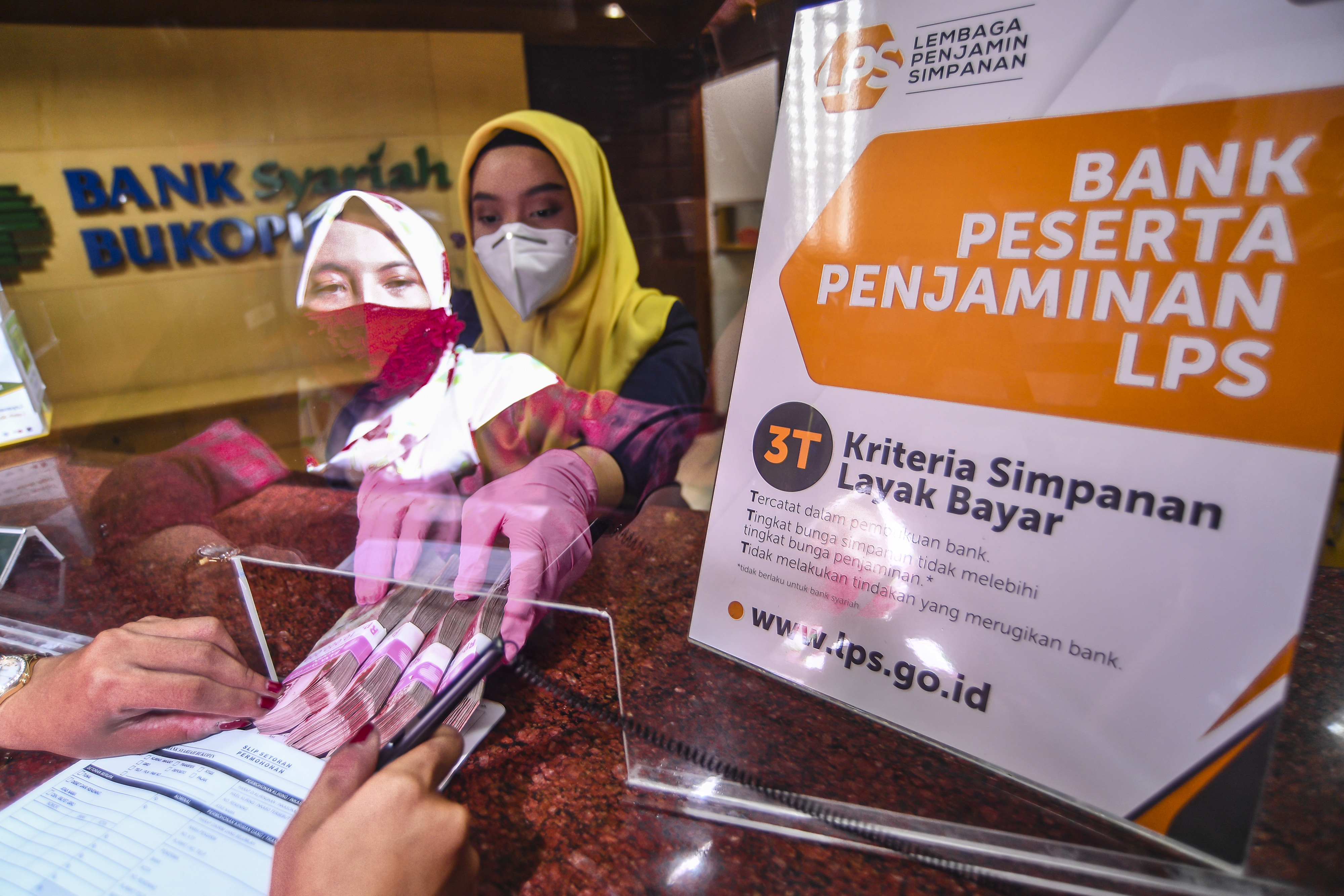 Ilustrasi karyawan bank peserta penjaminan LPS saat melayani nasabah.