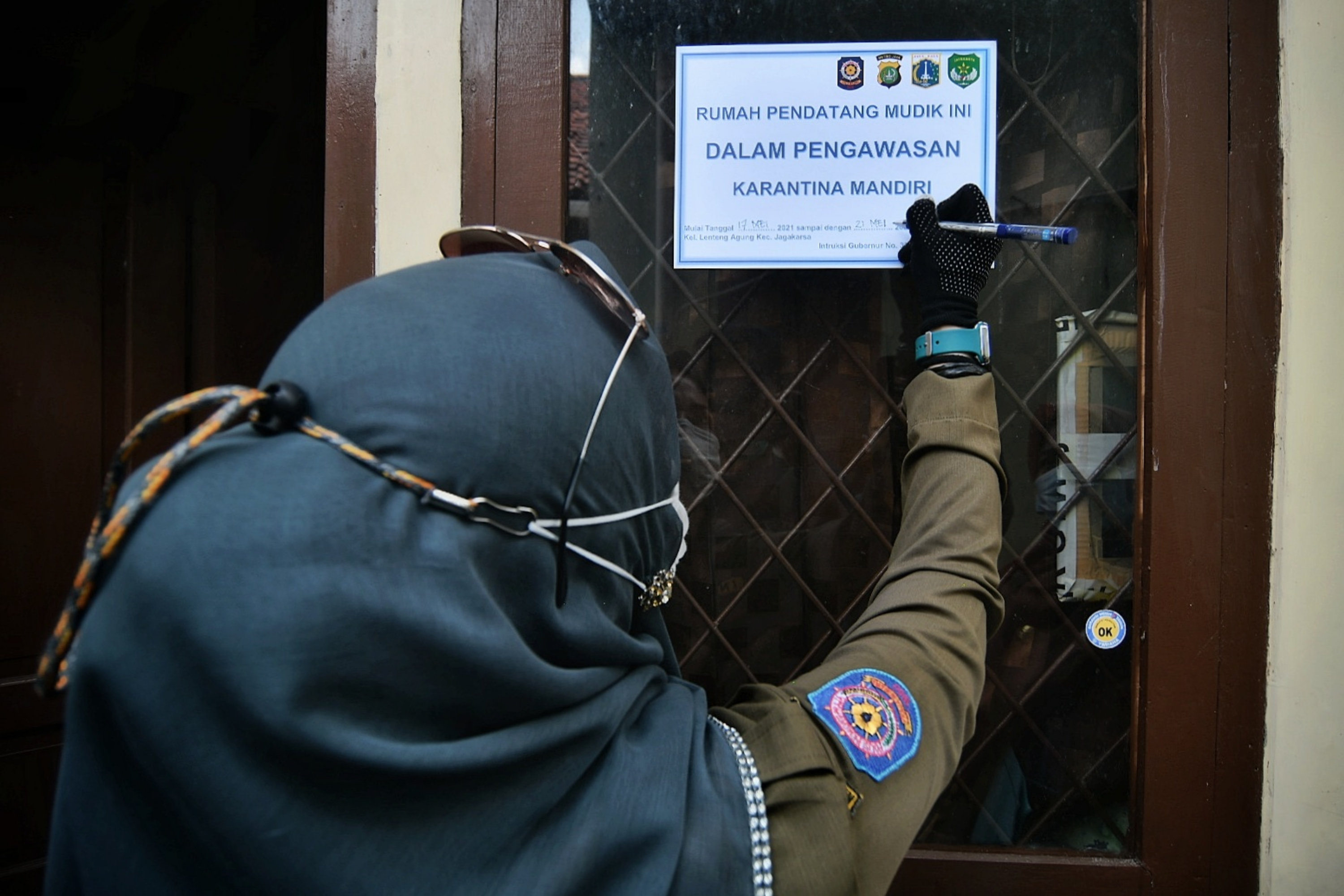Aparat memasang stiker di rumah pemudik yang baru balik ke jakarta