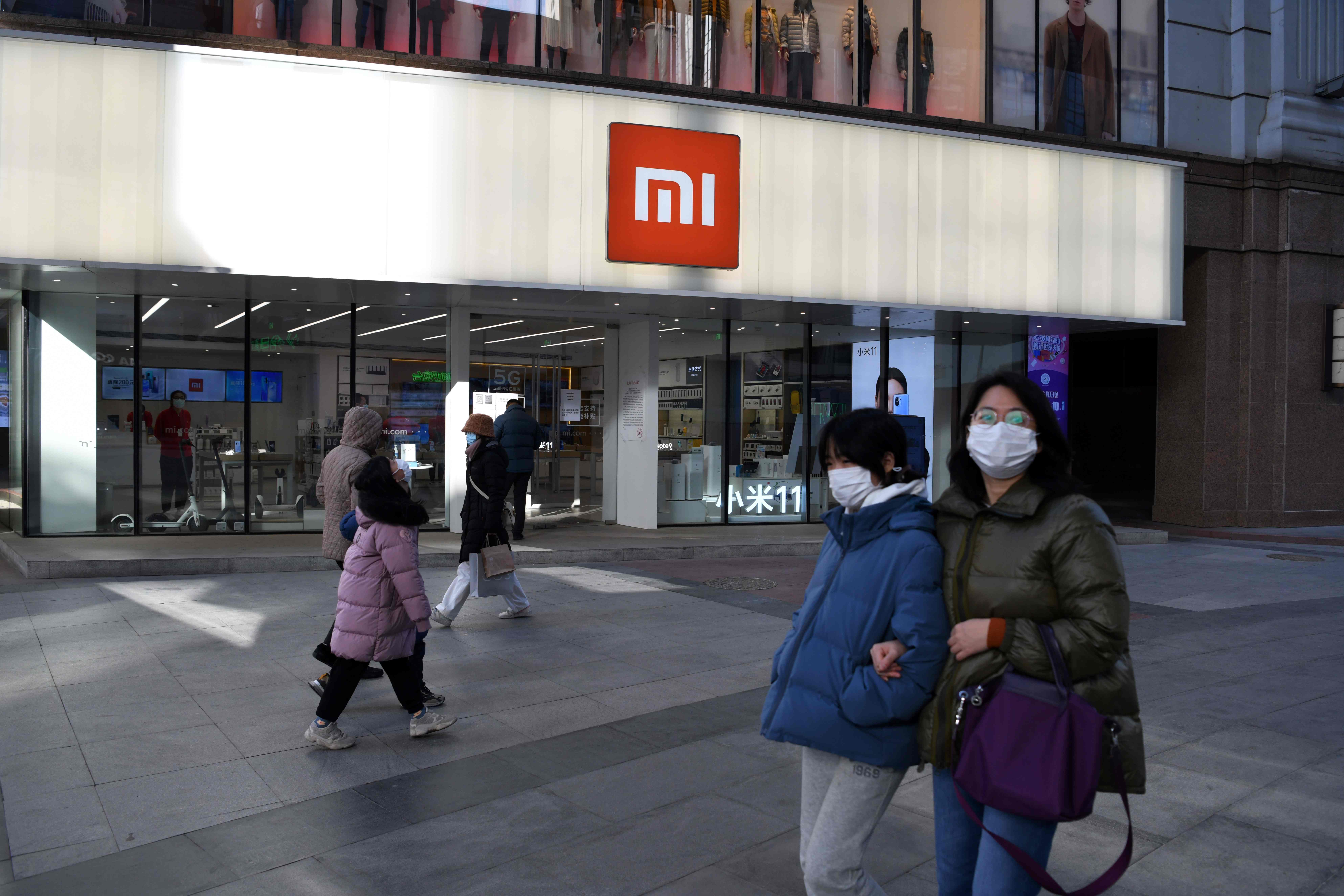 Sejumlah orang melintasi toko yang dimiliki perusahaan Xiaomi di Kota Beijing, Tiongkok.
