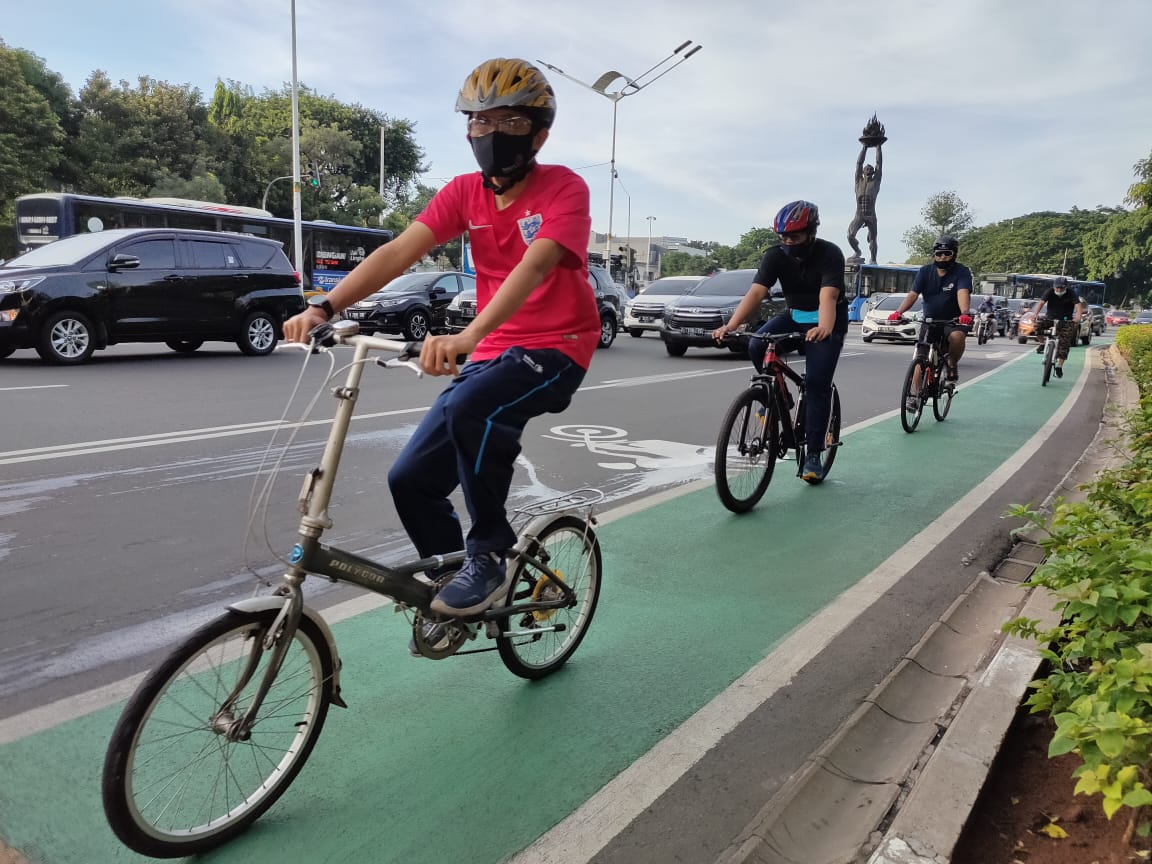 Para pesepeda melintasi Jalan Sudirman lewat jalur khusus sepeda.