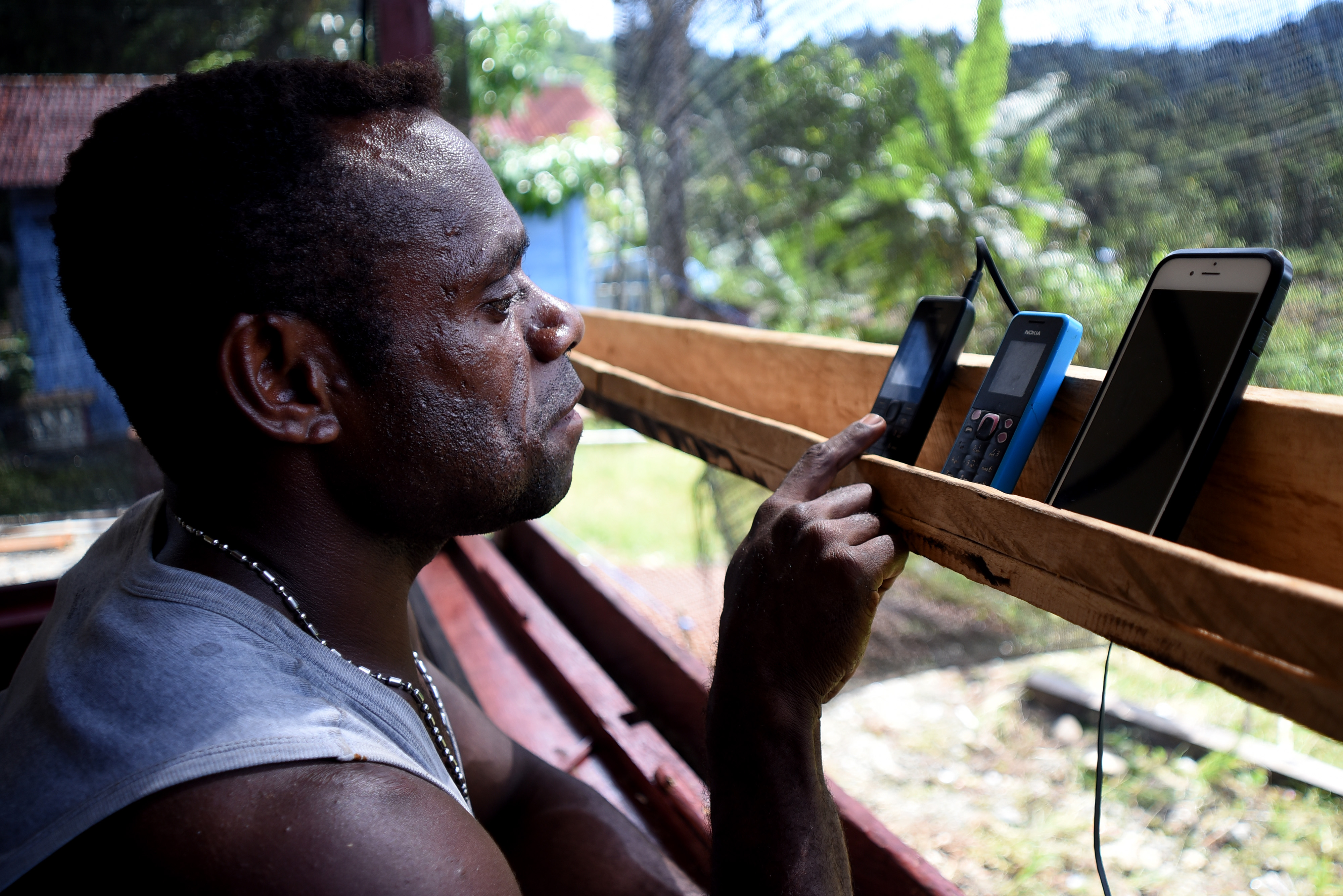  Seorang warga menerima panggilan masuk melalui telepon genggamnya di pelosok Mosairo, Nabire, Papua.