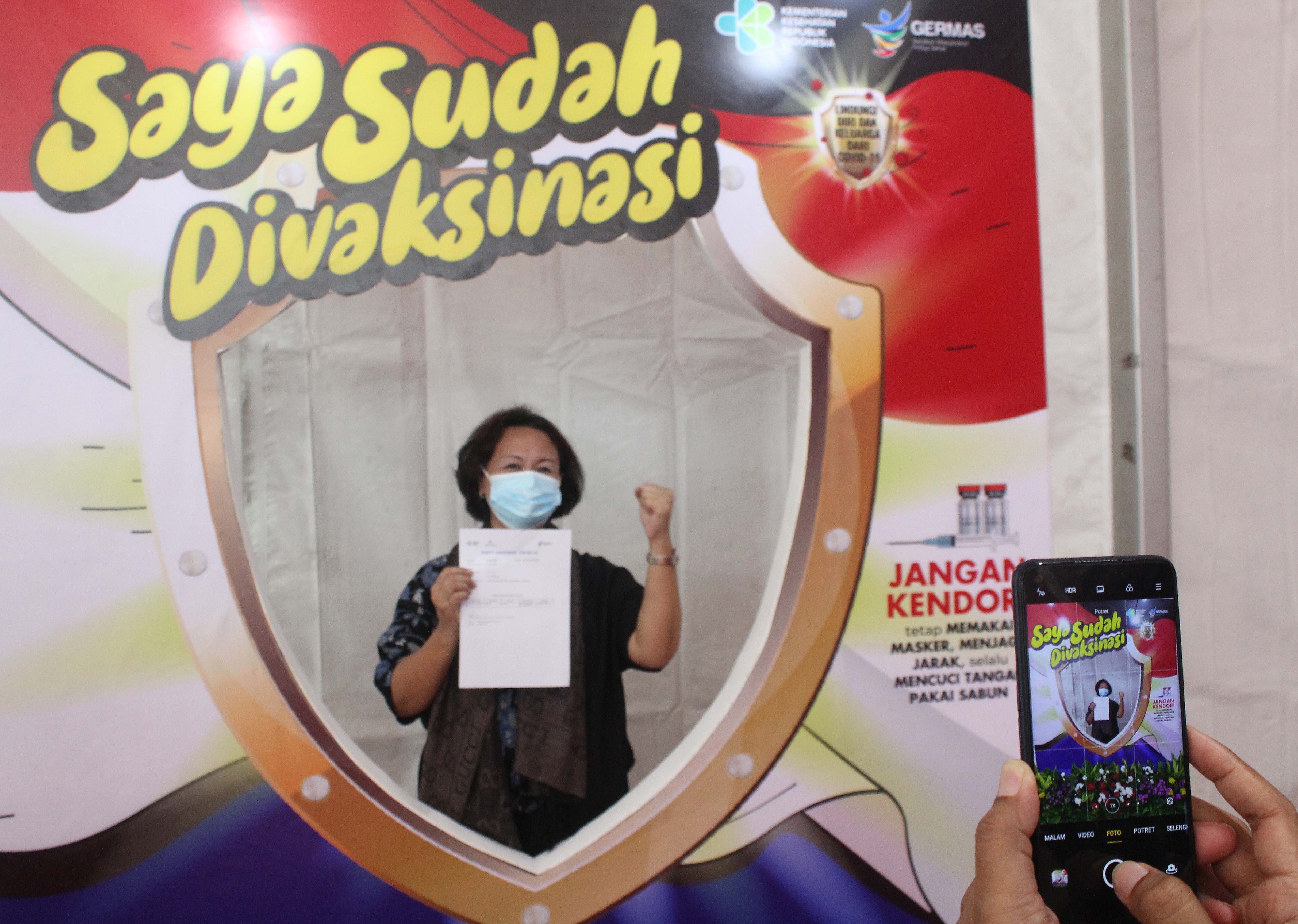 Seorang tenaga pendidikan berfoto setelah menjalani vaksinasi covid-19 di SMA Negeri 70 Jakarta, Jakarta, Rabu (24/2/2021)