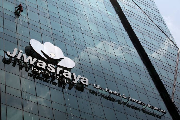 Pekerja membersihkan kaca gedung berlogo Asuransi Jiwasraya di Jakarta