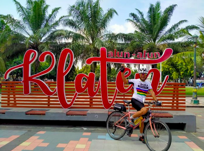 Seorang pesepeda berpose di depan papan nama Alun-Alun Klaten.