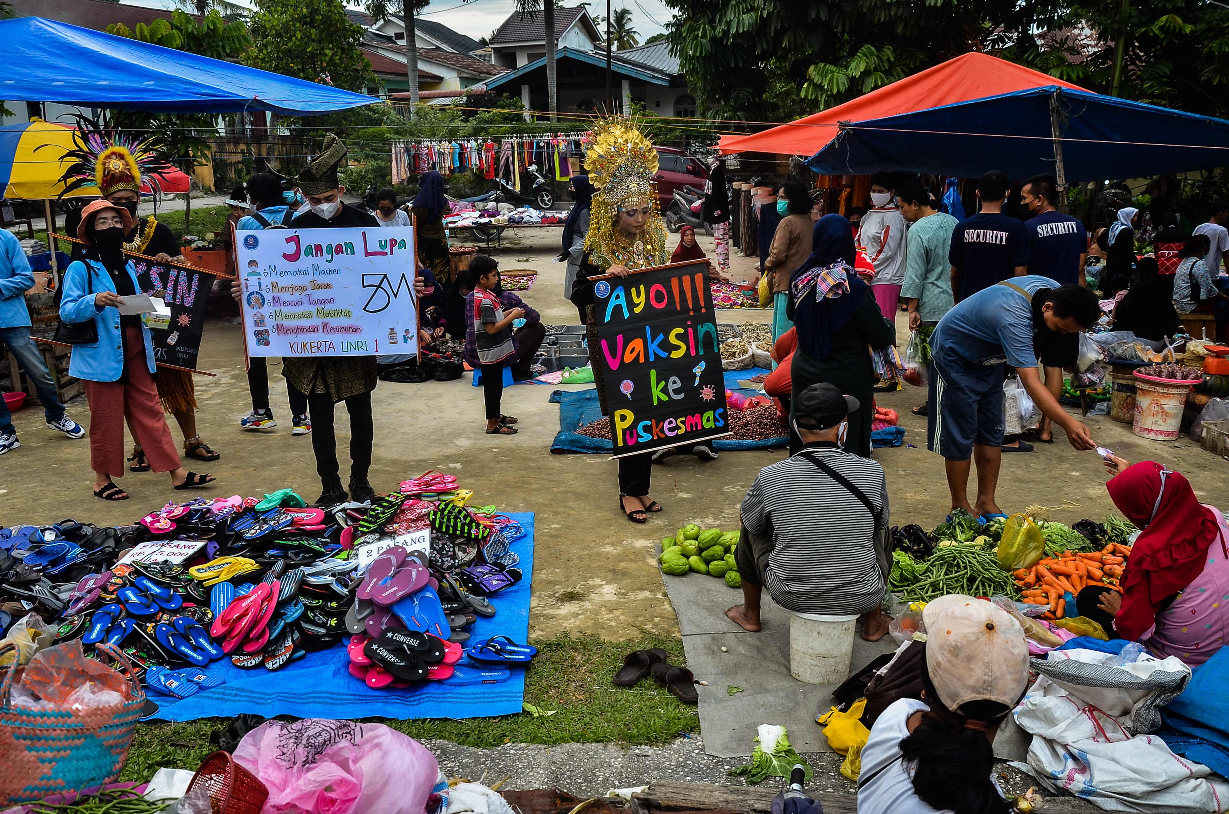 Sejumlah aktivis mengenakan pakaian tradisional mempromosikan kewaspadaan covid-19 di sebuah pasar di Pekanbaru, Riau.