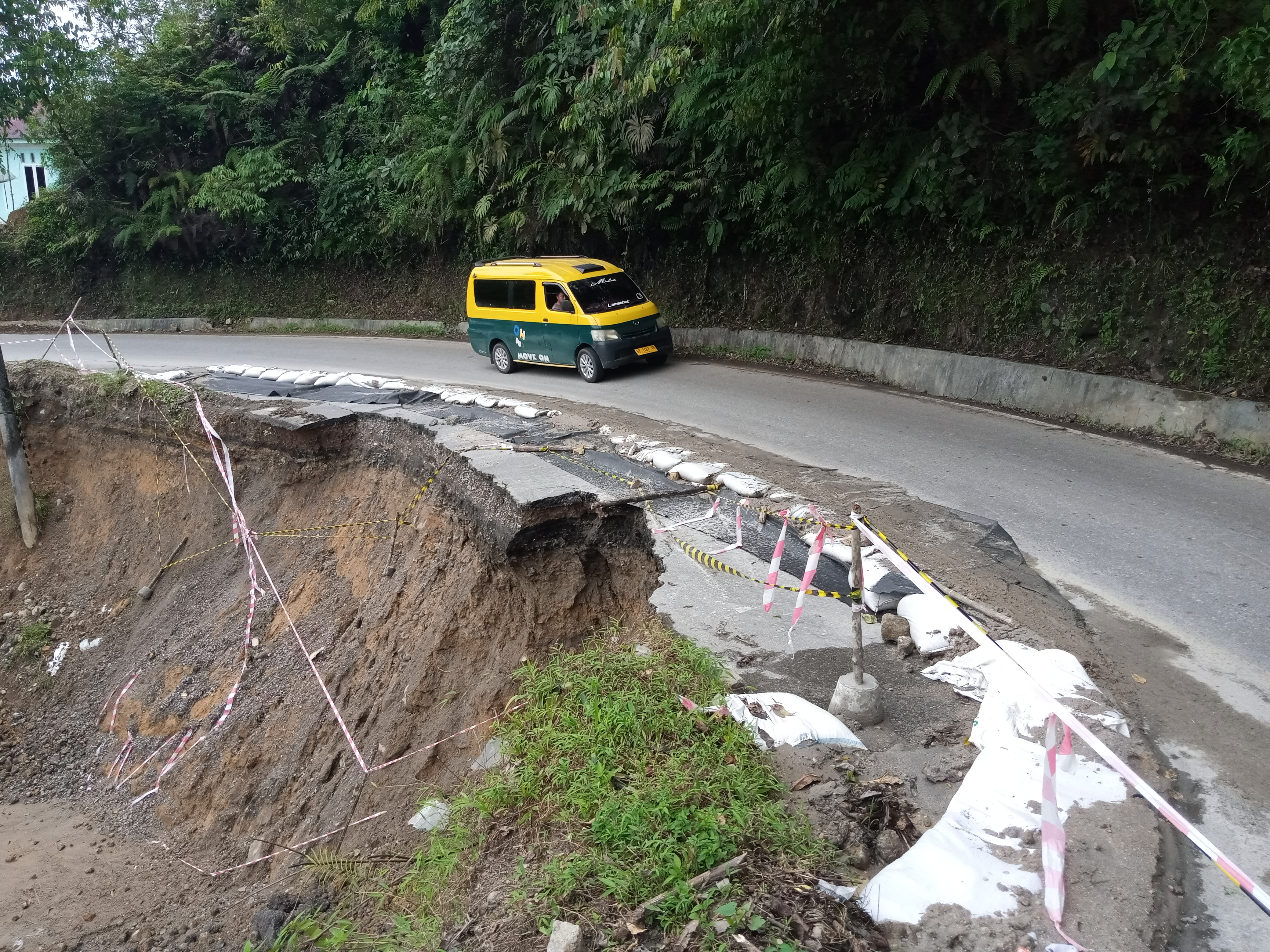 Angkutan umum melintas jalinsum di Desa Pancur Napitu Kecamatan Siatas Barita yang terancam putus, akibat longsor.
