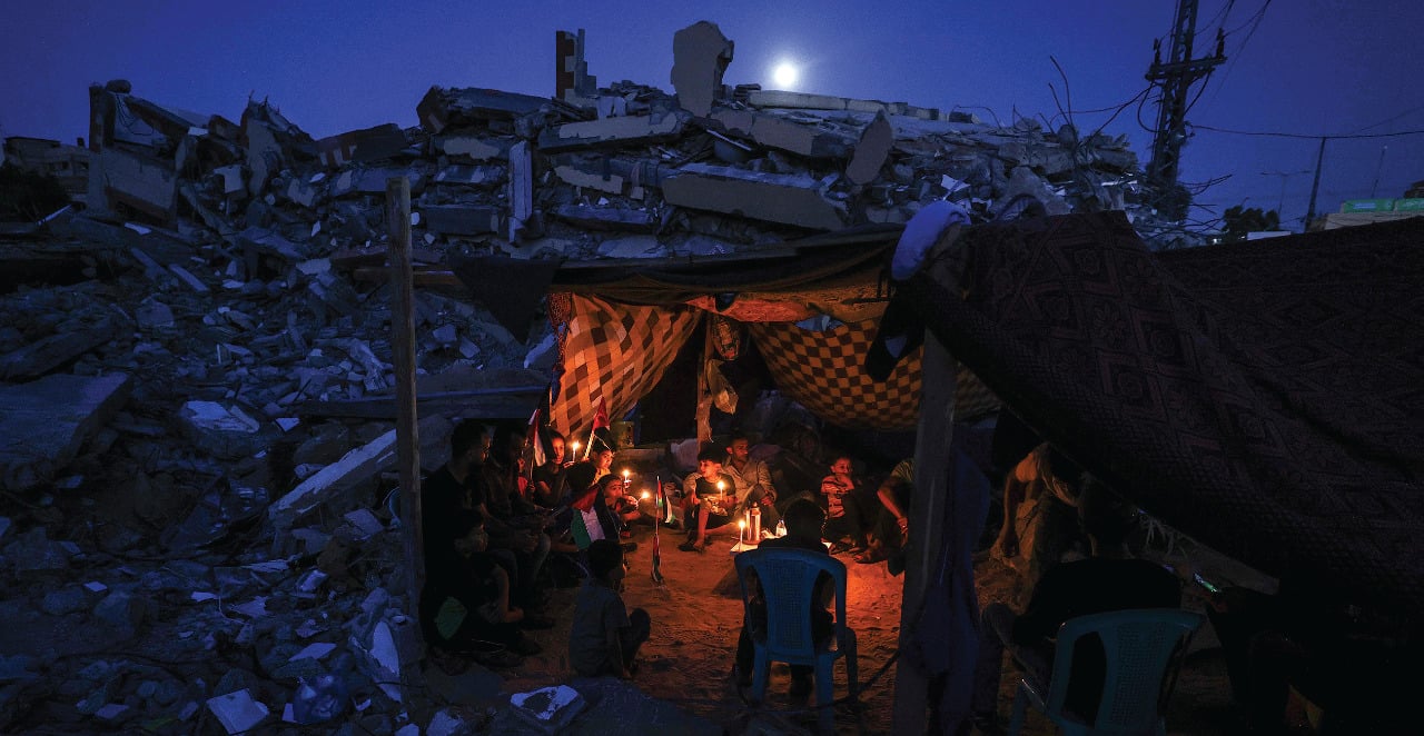 Warga menyalakan lilin di tenda yang didirikan di antara reruntuhan sebuah bangunan yang hancur dalam serangan udara Israel, di Beit Lahia.