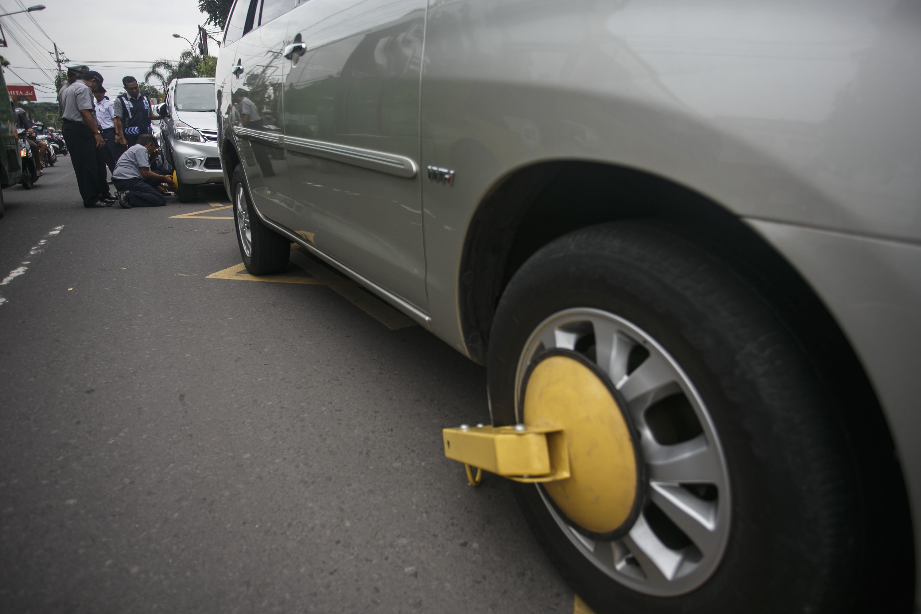 Petugas menggembok ban mobil saat penertiban parkir liar di Jalan Cik Ditiro, Yogyakarta, DI Yogyakarta, 