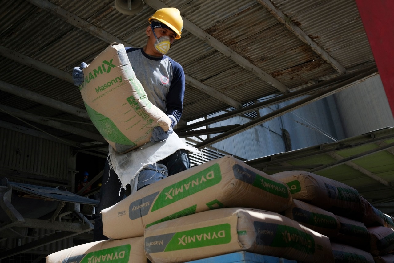 Pekerja mengangkat semen produksi SIG