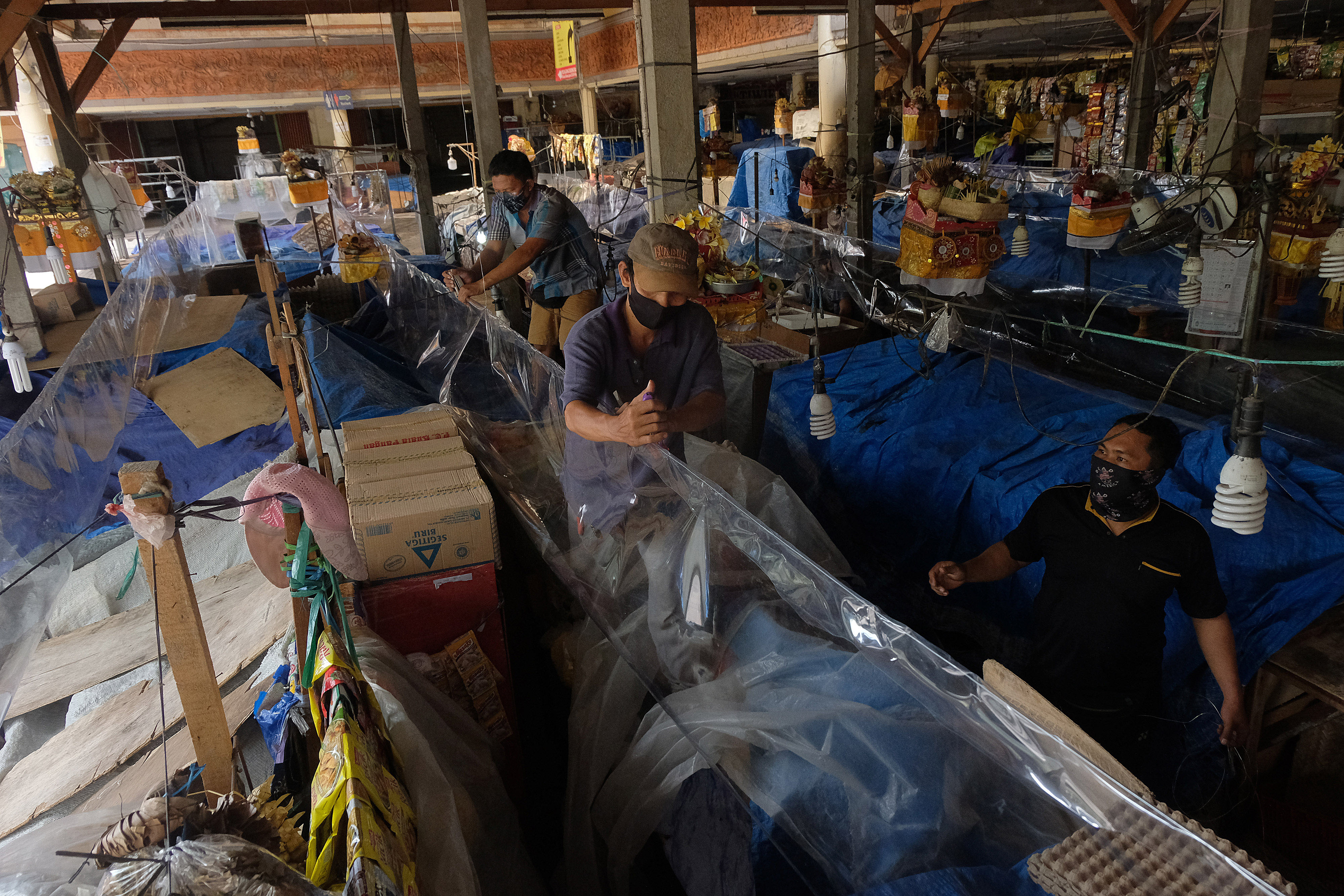 Petugas memasang plastik mika untuk menyekat lapak pedagang di pasar tradisional Cokroaminoto Denpasar, Bali, Senin (15/6/2020)