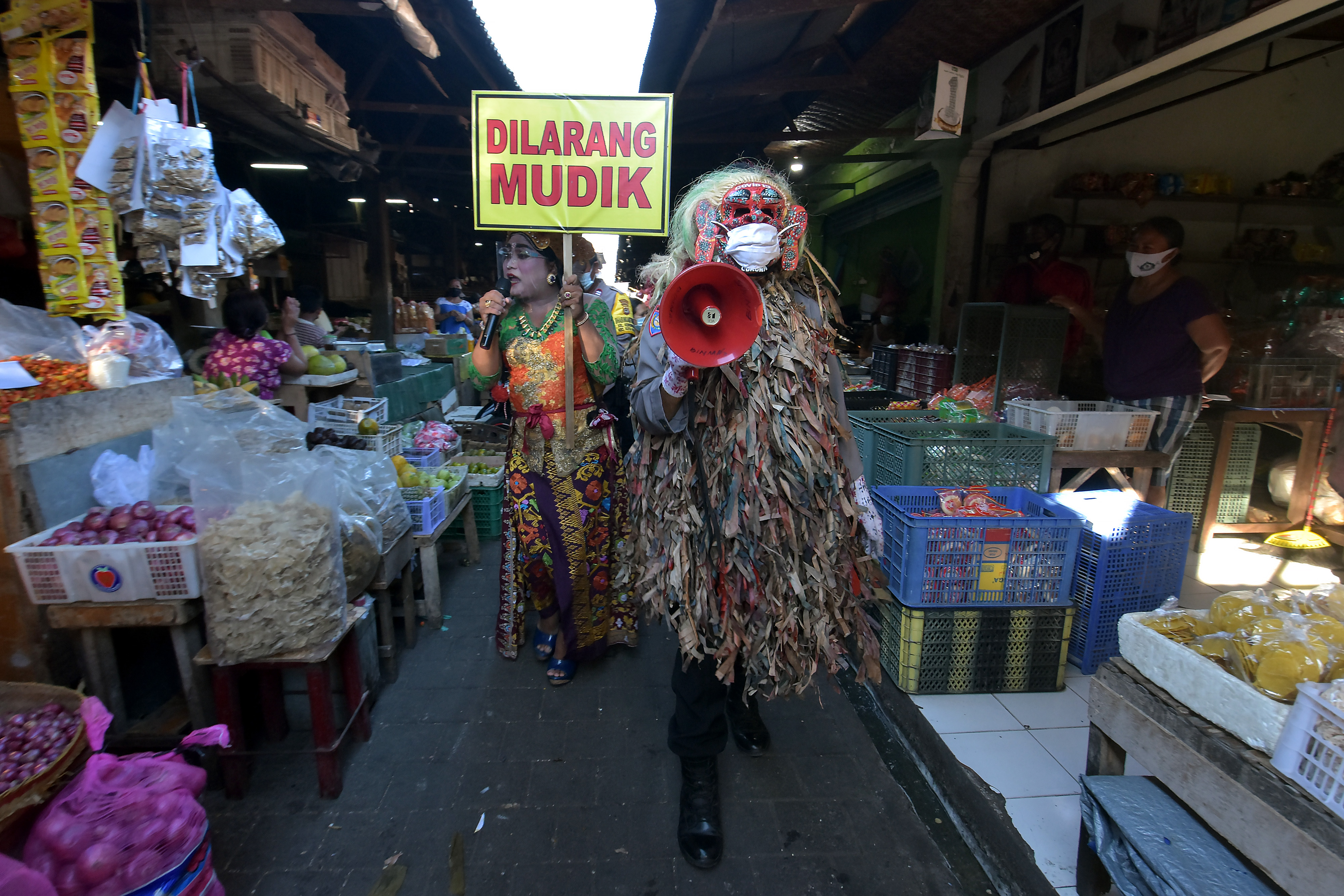 Polisi berkostum celuluk berkeliling pasar saat edukasi larangan mudik di Pasar Taman Sari Merta Kerobokan, Badung, Bali, Selasa (11/5/2021)