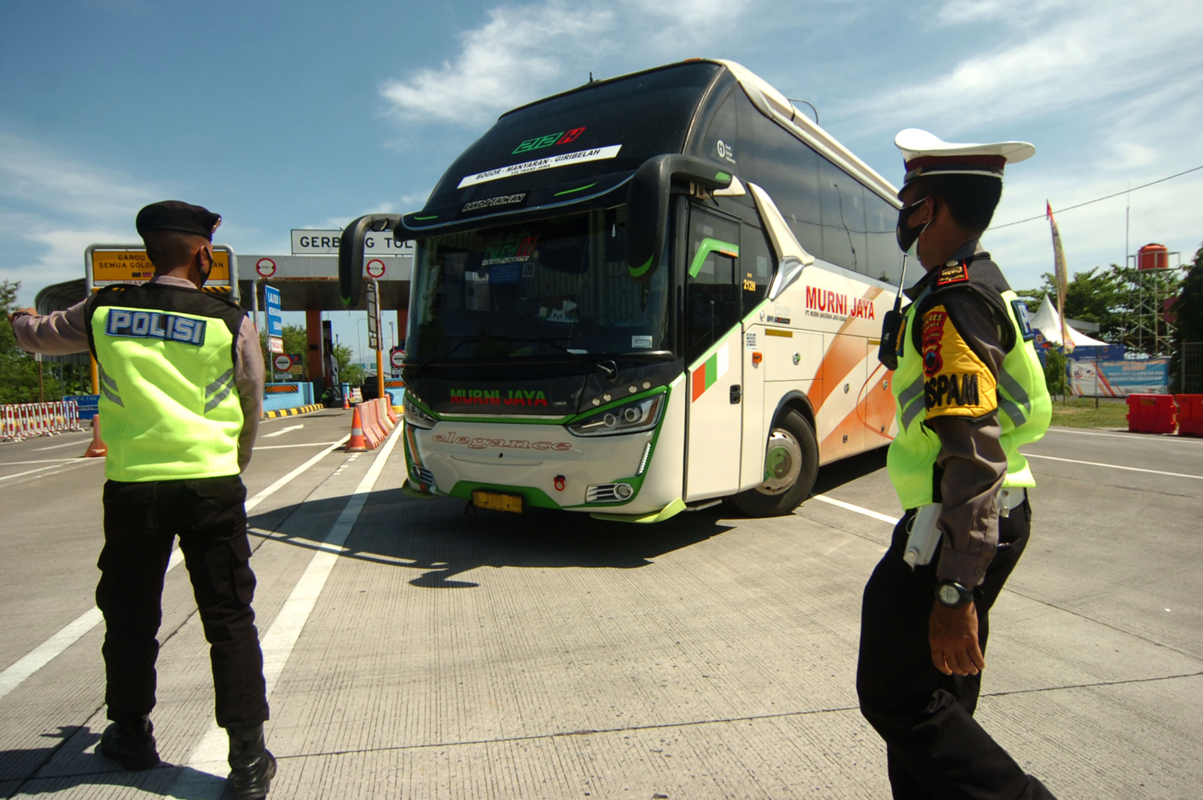 Petugas kepolisian memutar balik bus yang keluar di pintu tol.