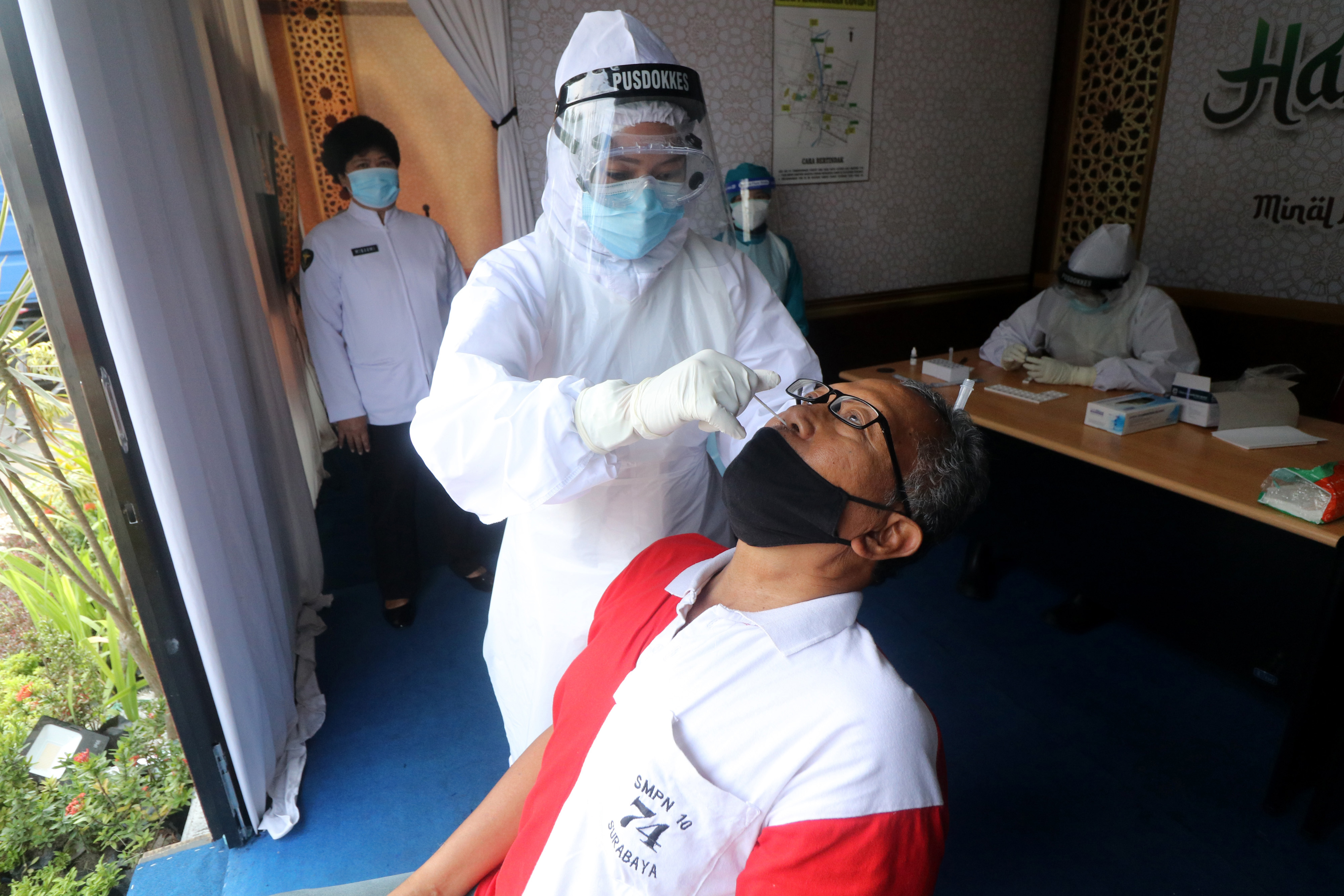 Ilustrasi. Petugas medis melakukan swab antigen kepada seorang warga.