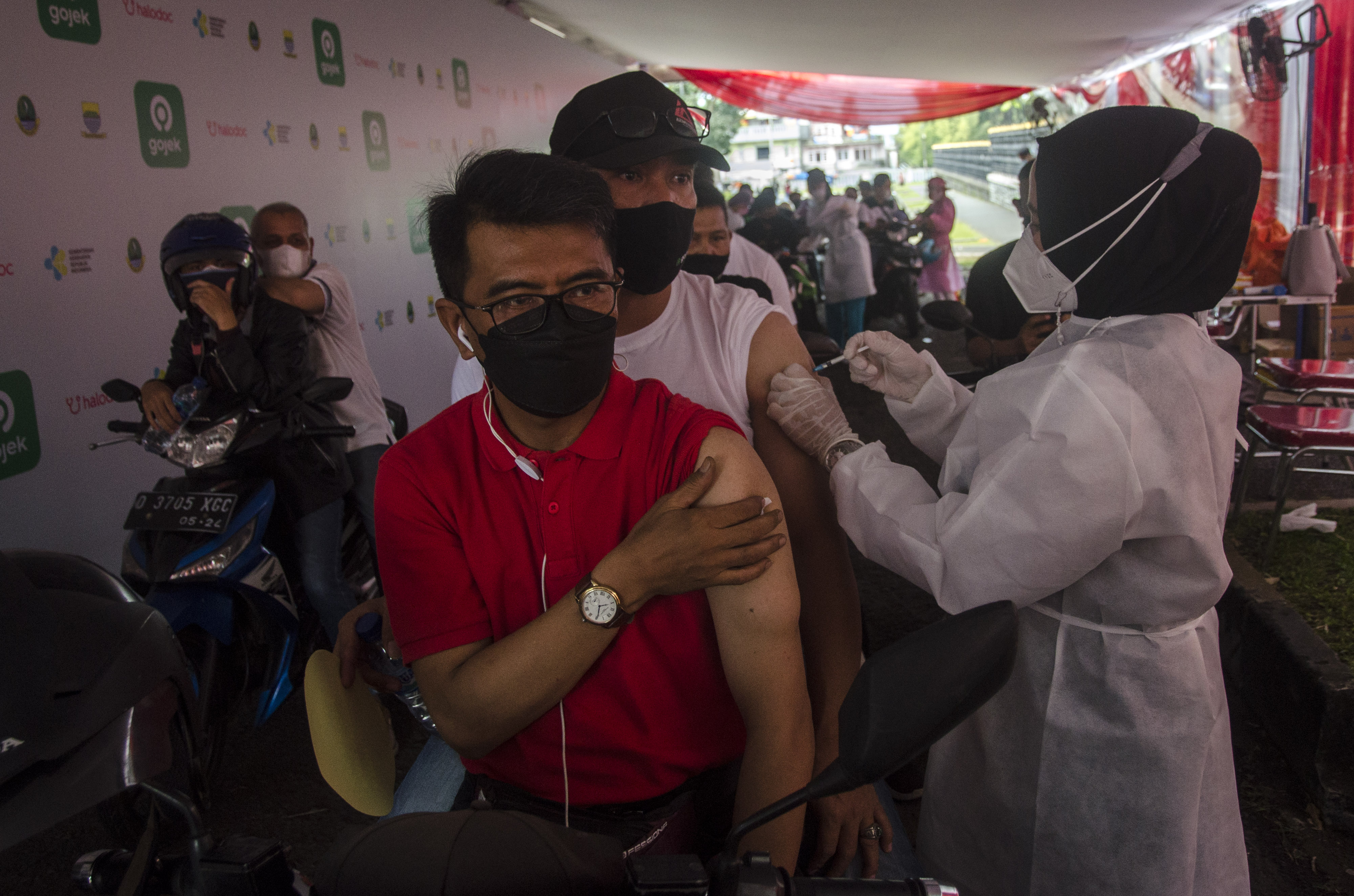 Petugas menyuntikkan vaksin covid-19 kepada mitra Gojek pada layanan Vaksinasi Drive Thru Gojek dan Halodoc di Bandung, Kamis (27/5/2021).
