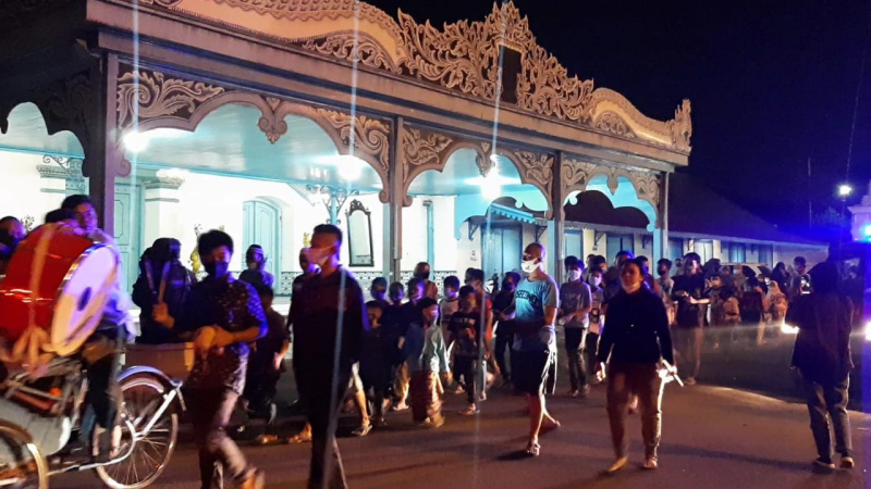 Peserta takbir keliling dari masjid dalam tembok besar Kraton Kasunanan Surakarta berjalan tertib melewati depan Kori Kamandungan.