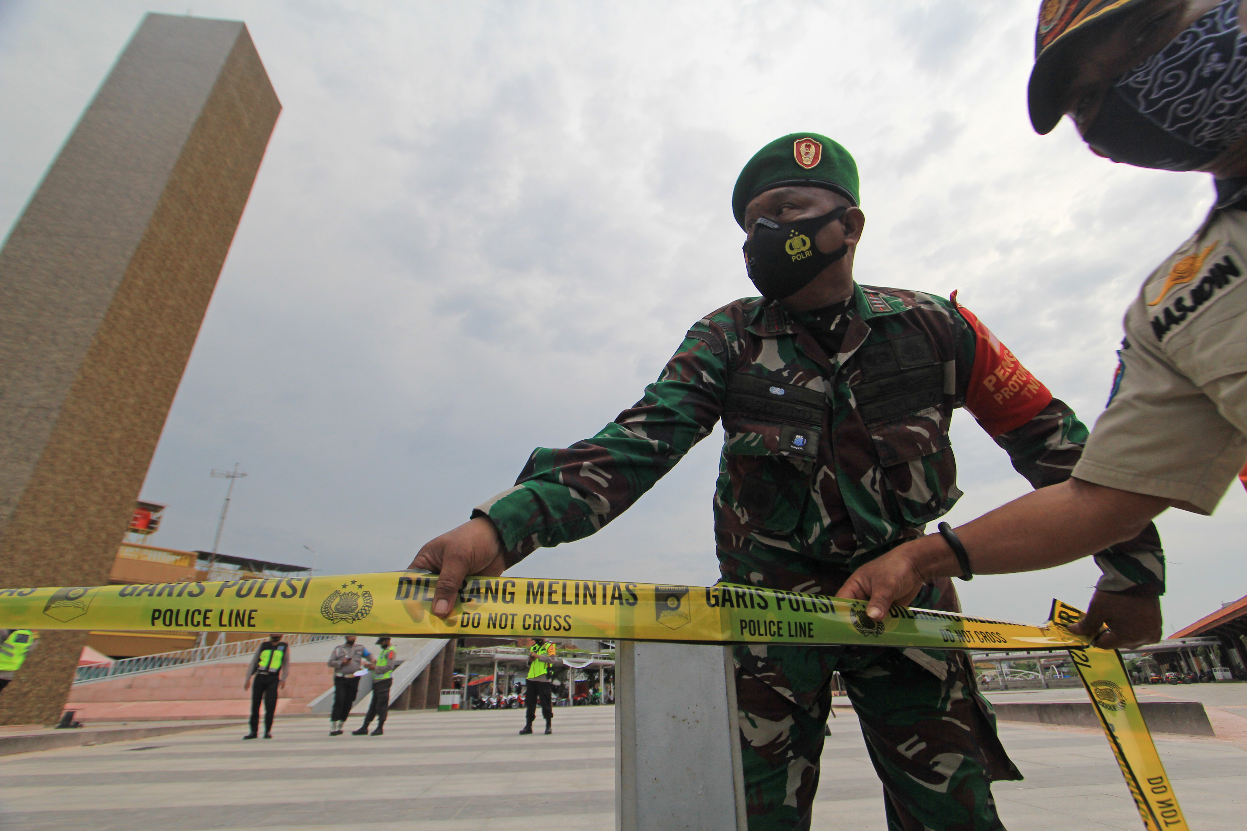 etugas gabungan memasang garis polisi di ruang terbuka Jatibarang, Indramayu, Jawa Barat