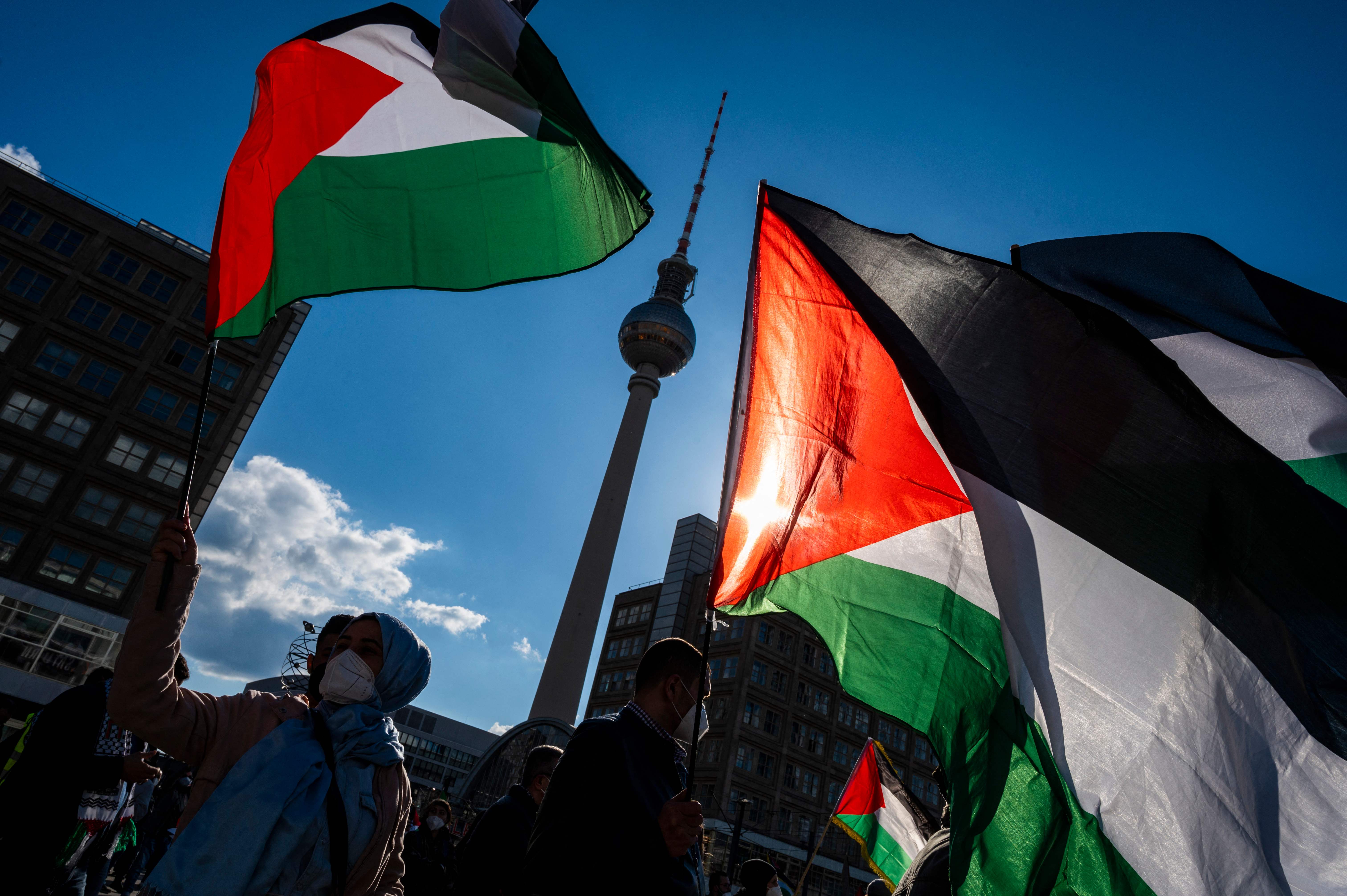 Sejumlah demonstran memegang bendera Palestina saat berunjuk rasa.