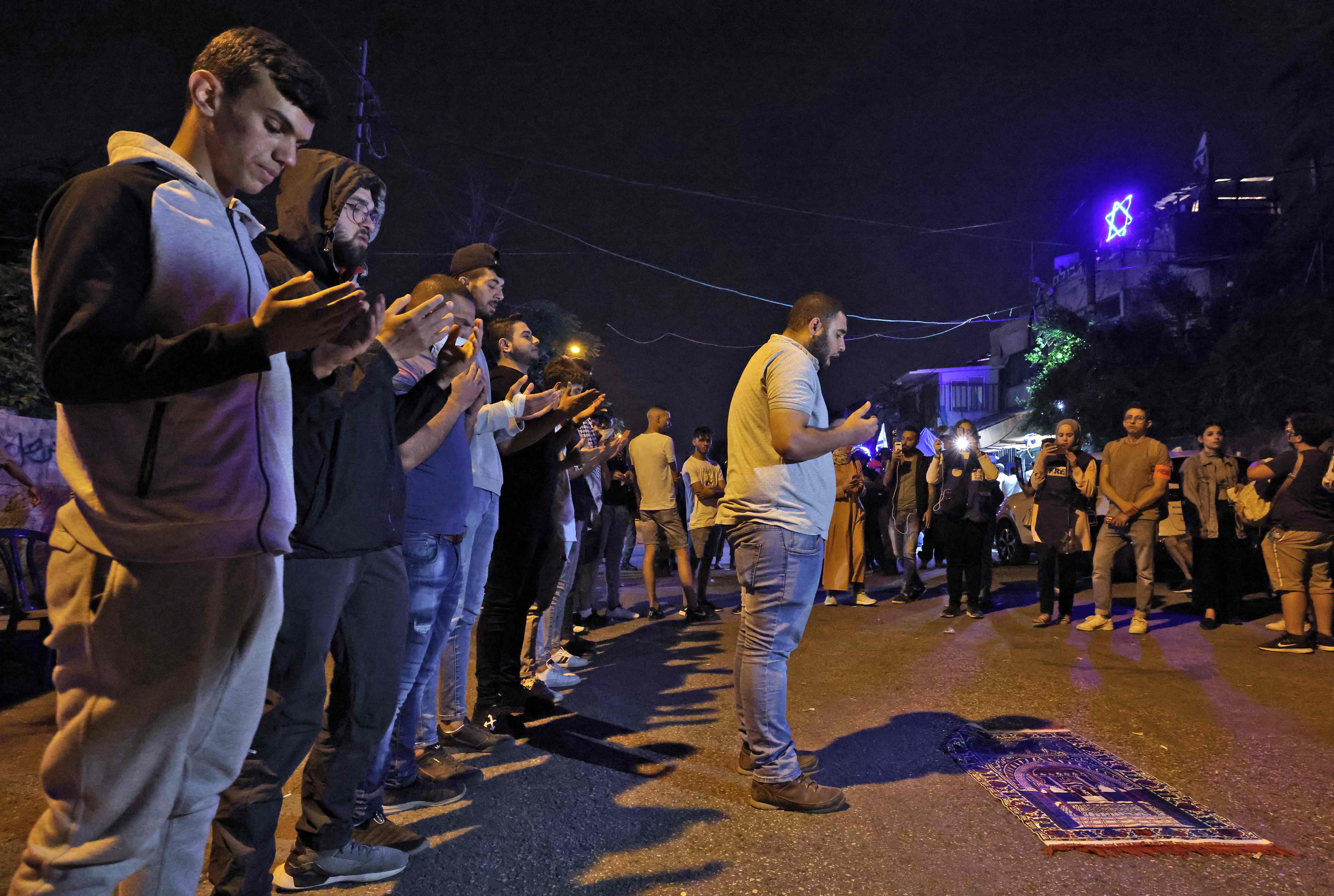 Warga Palestina melakukan salat di jalan di depan permukiman Israel di Sheikh Jarrah, Jerusalem.