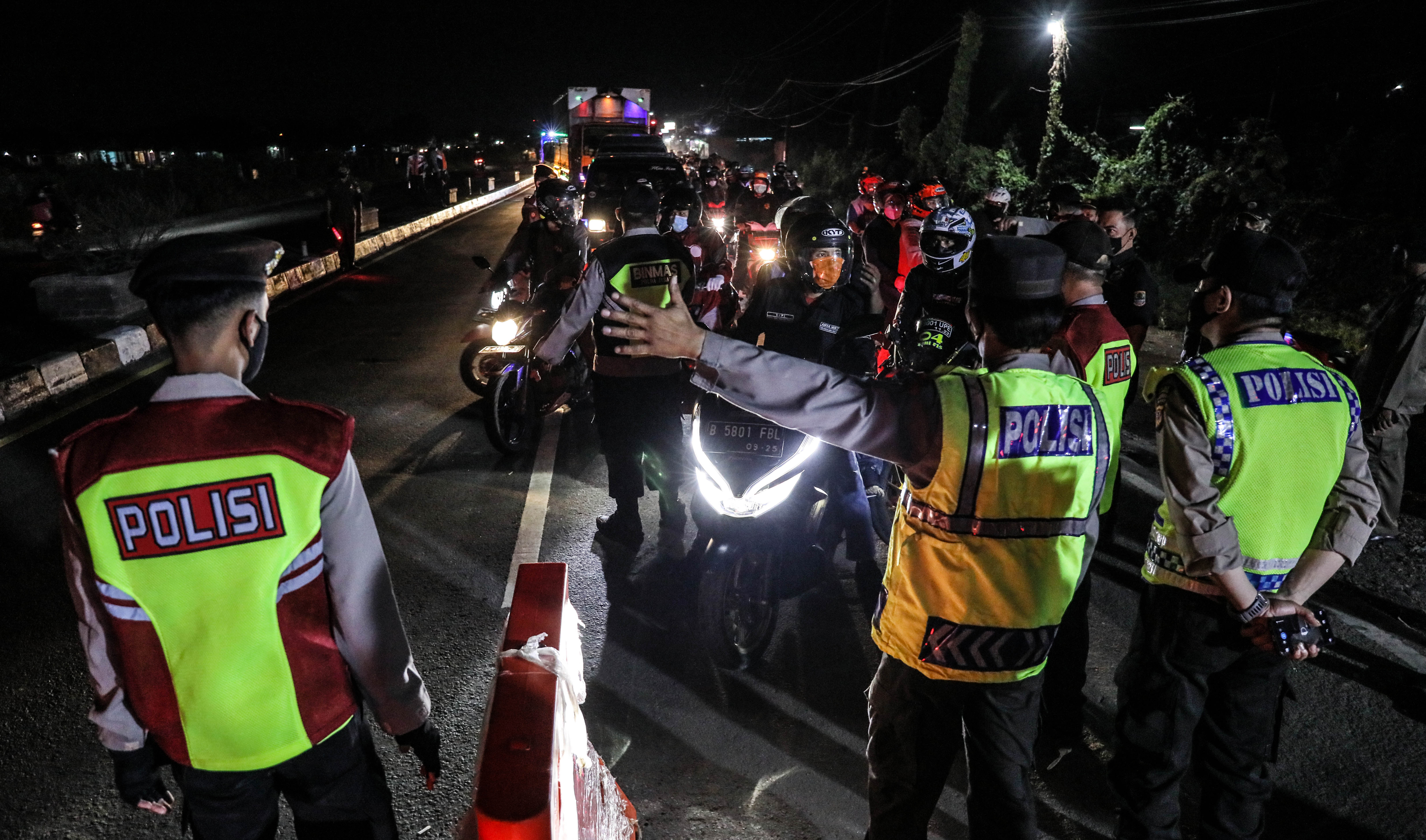 Petugas kepolisian melakukan pemeriksaan kepada pemudik sepeda motor saat penyekatan larangan mudik di Pos Polisi Gamon