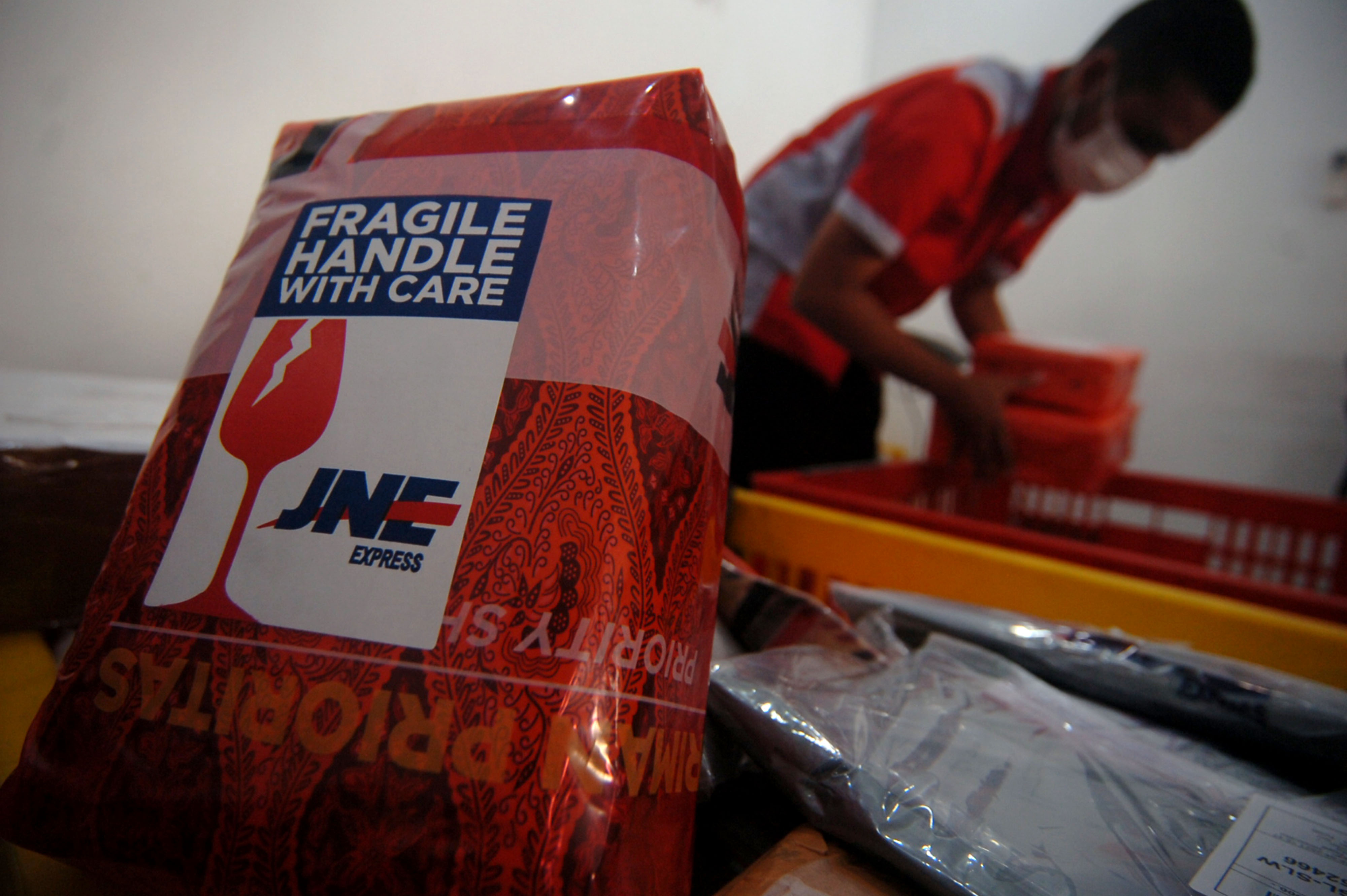 Ilustrasi petugas JNE menyortir paket yang akan dikirim ke alamat tujuan.