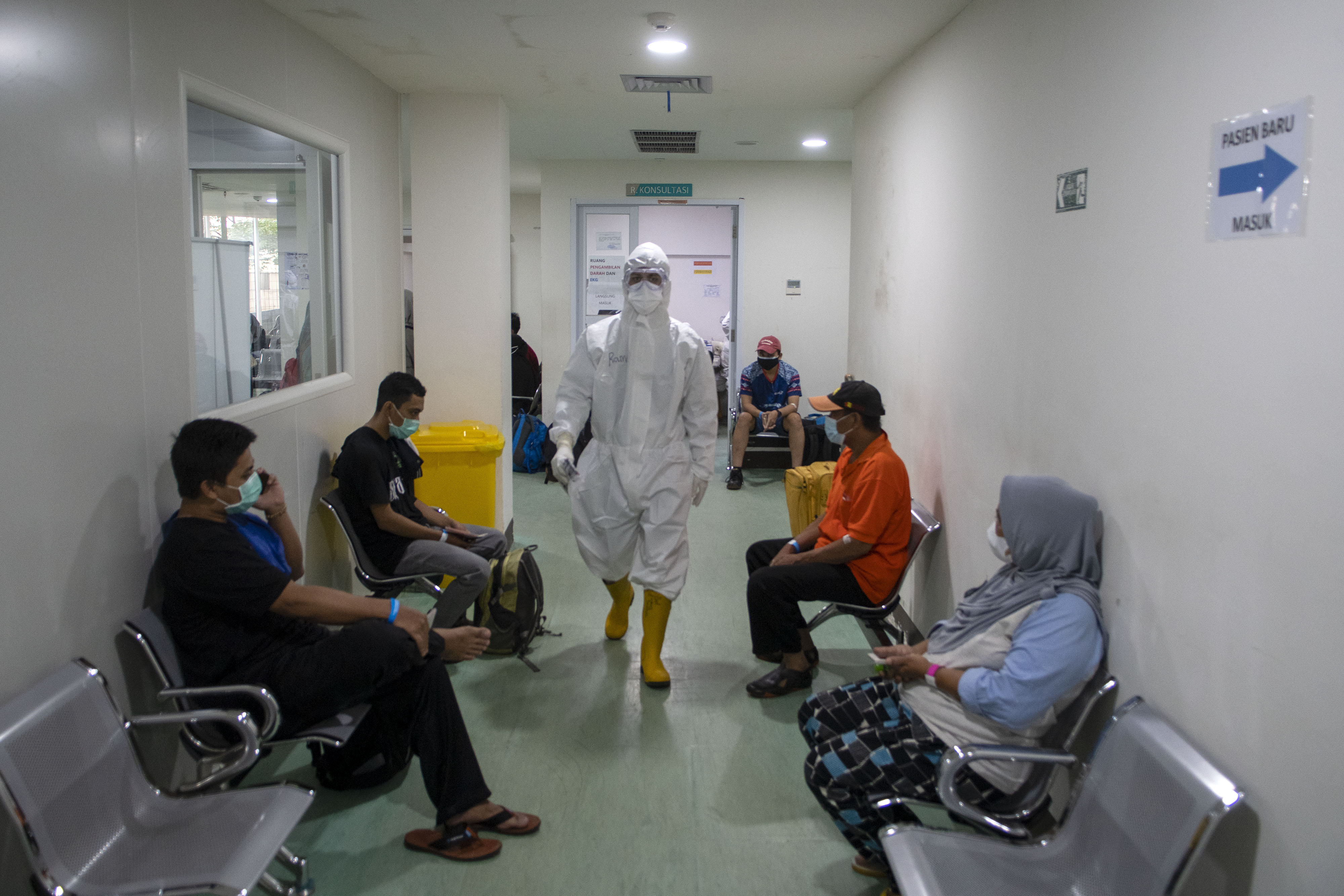 Seorang tenaga kesehatan berjalan di antara pasien positif COVID-19 yang baru tiba di Rumah Sakit Darurat COVID-19