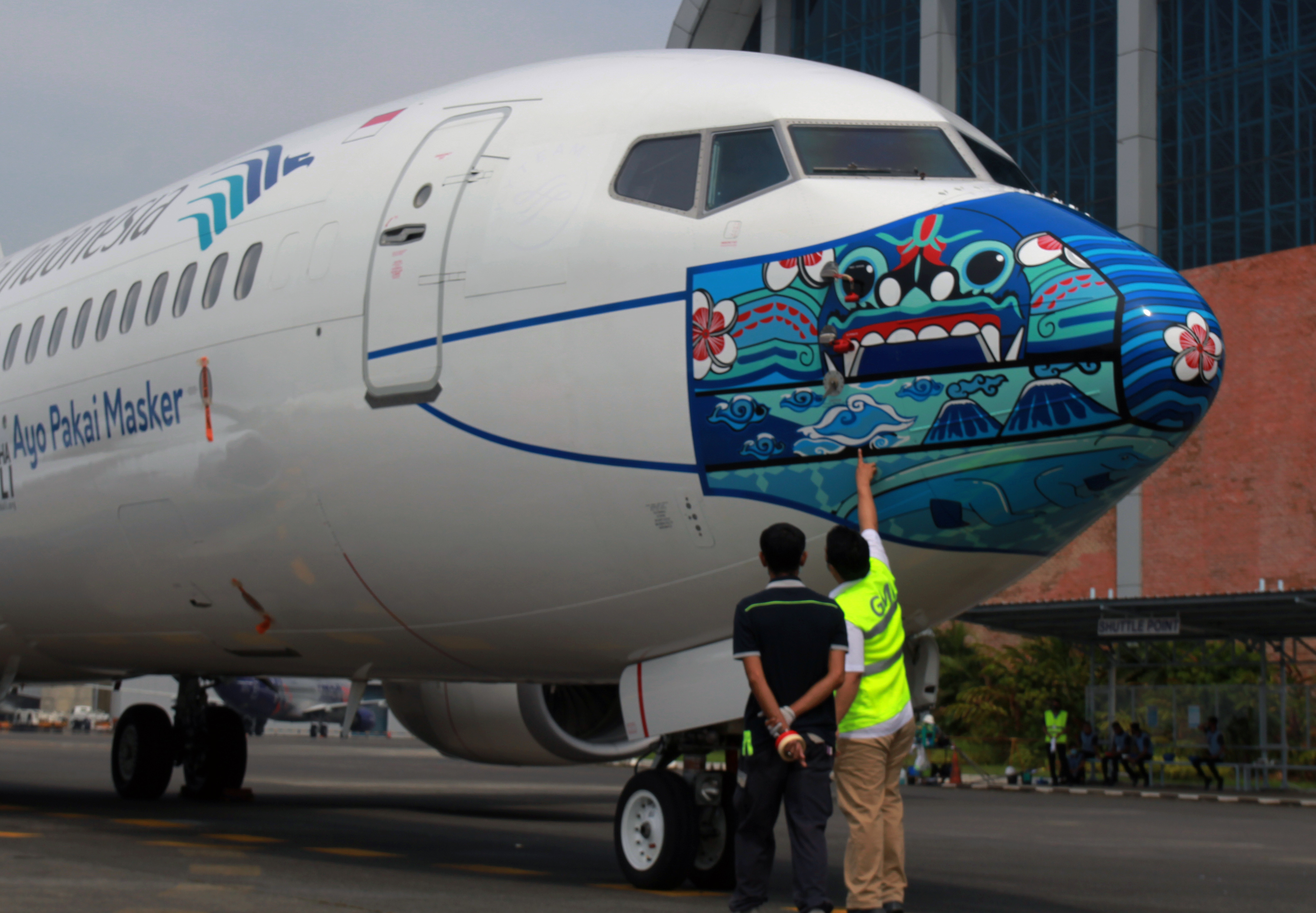 Pekerja melakukan pengecekan akhir livery masker di pesawat Garuda Indonesia.